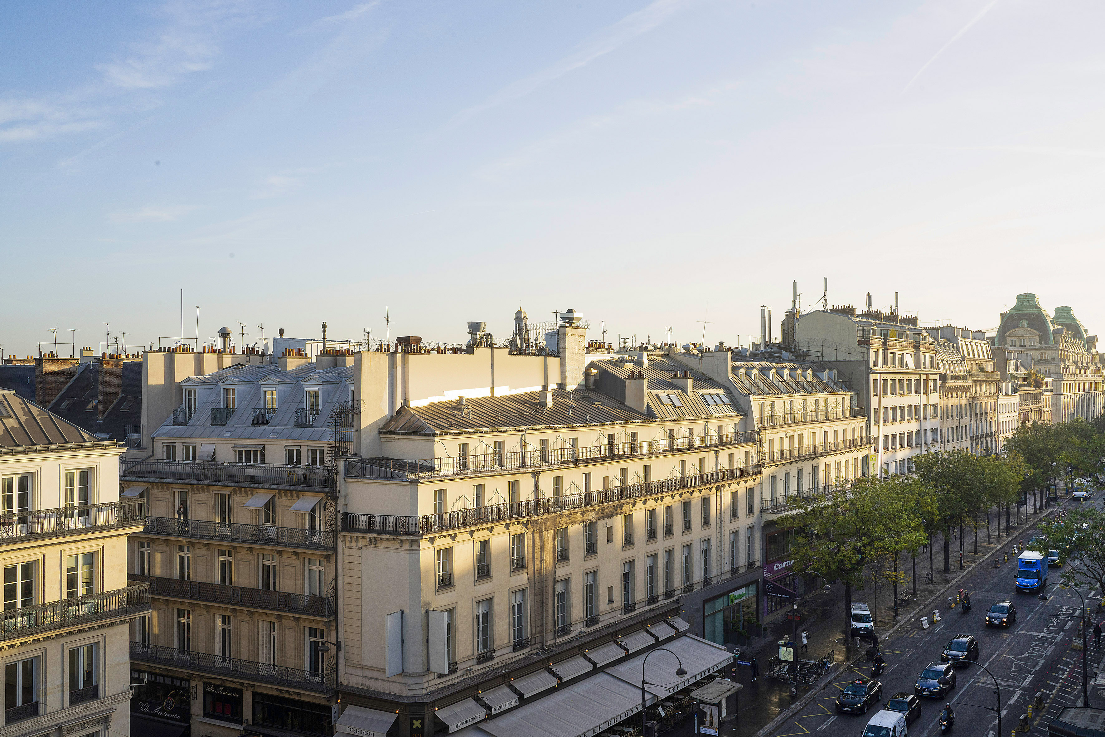 Aerial view of Paris Haussmannian buildings, rooftops, and street traffic.