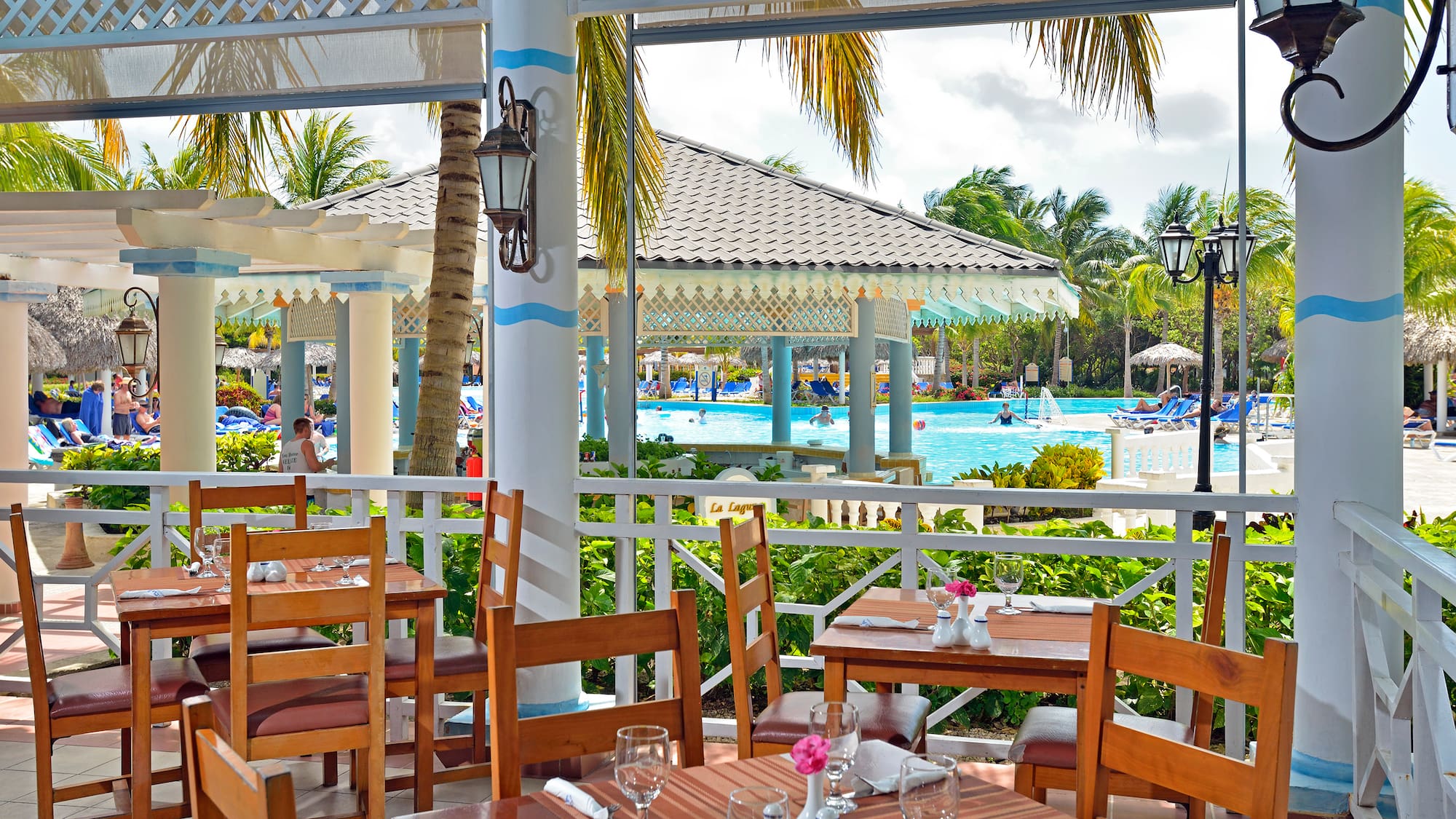 a restaurant with tables and chairs and a pool in the background