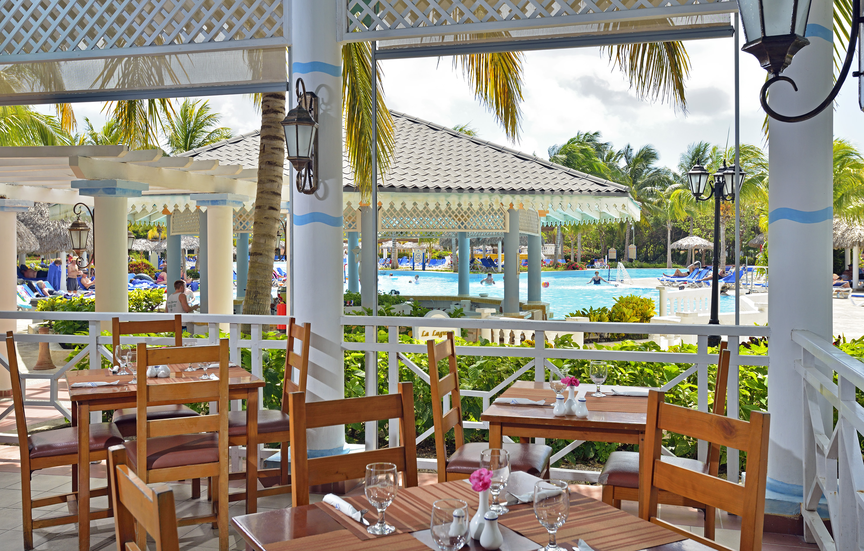 a restaurant with tables and chairs and a pool in the background