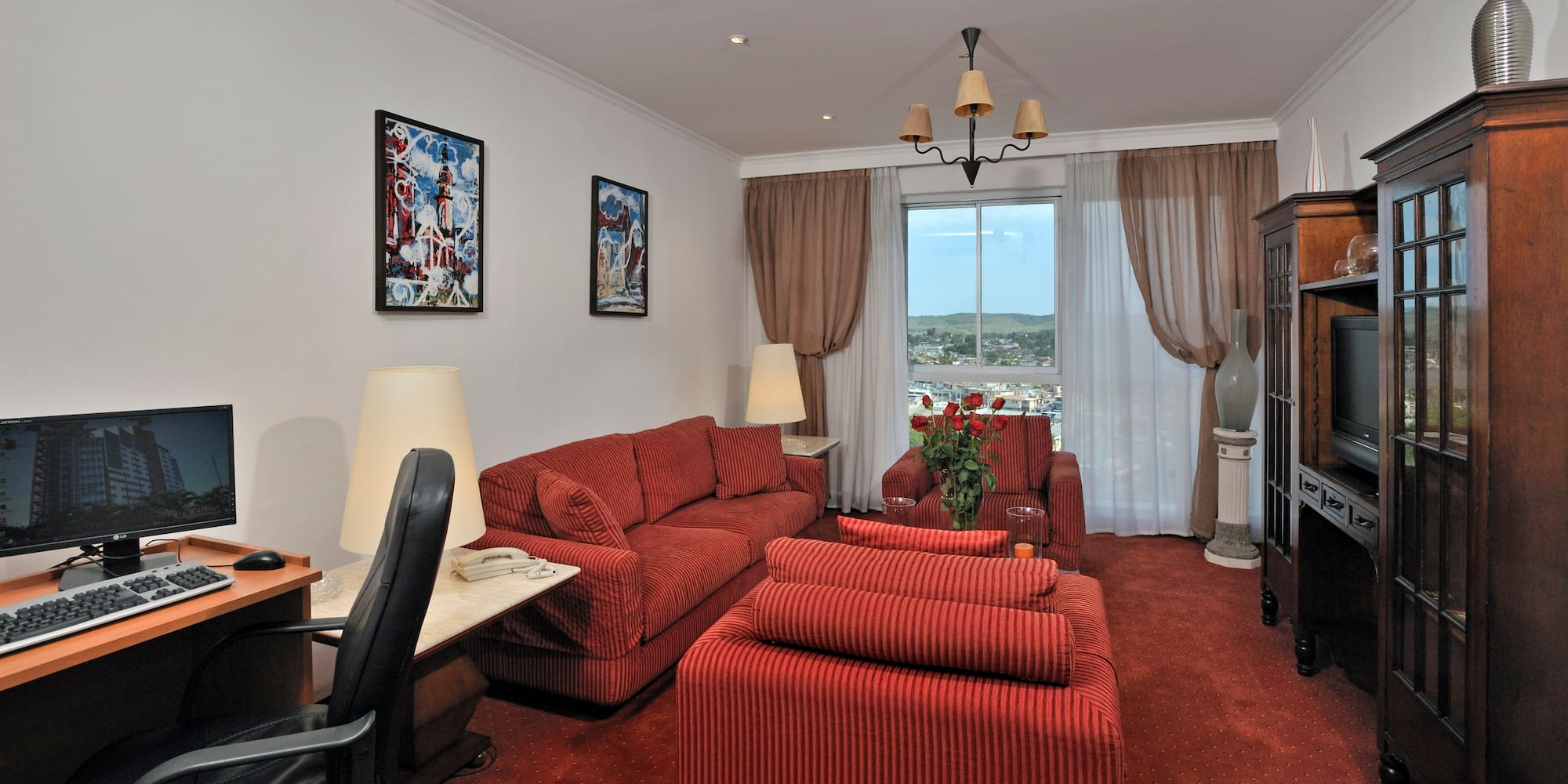 a living room with red couches and a desk