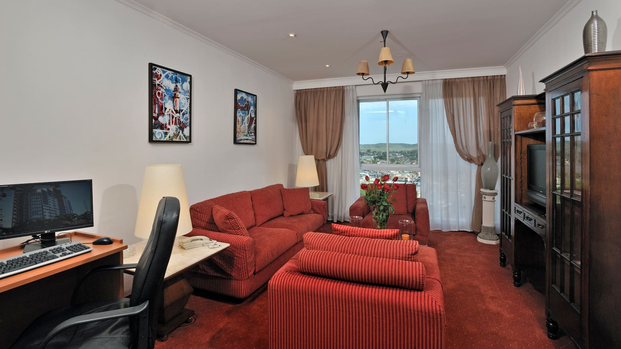 a living room with red couches and a desk