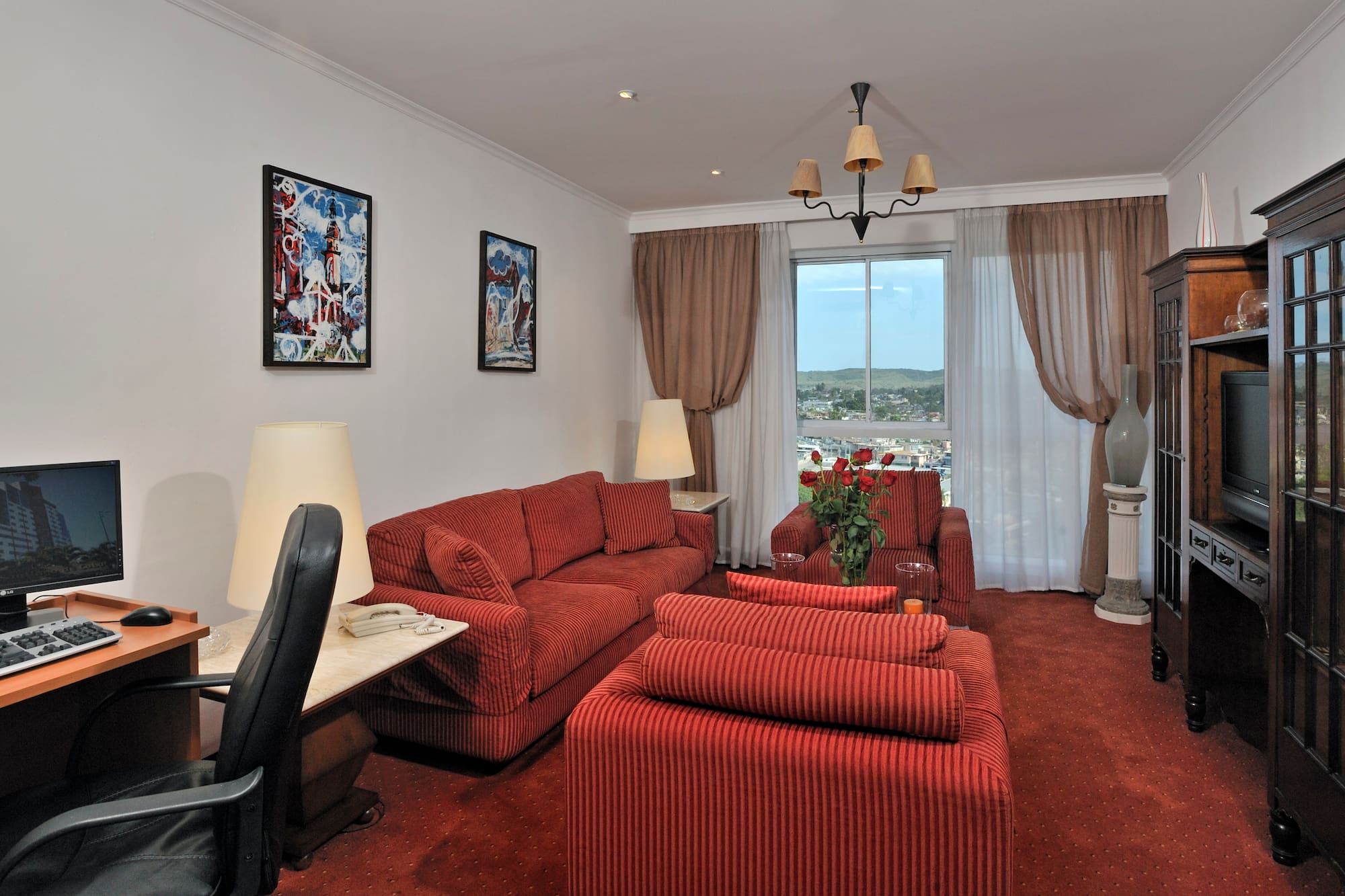 a living room with red couches and a desk