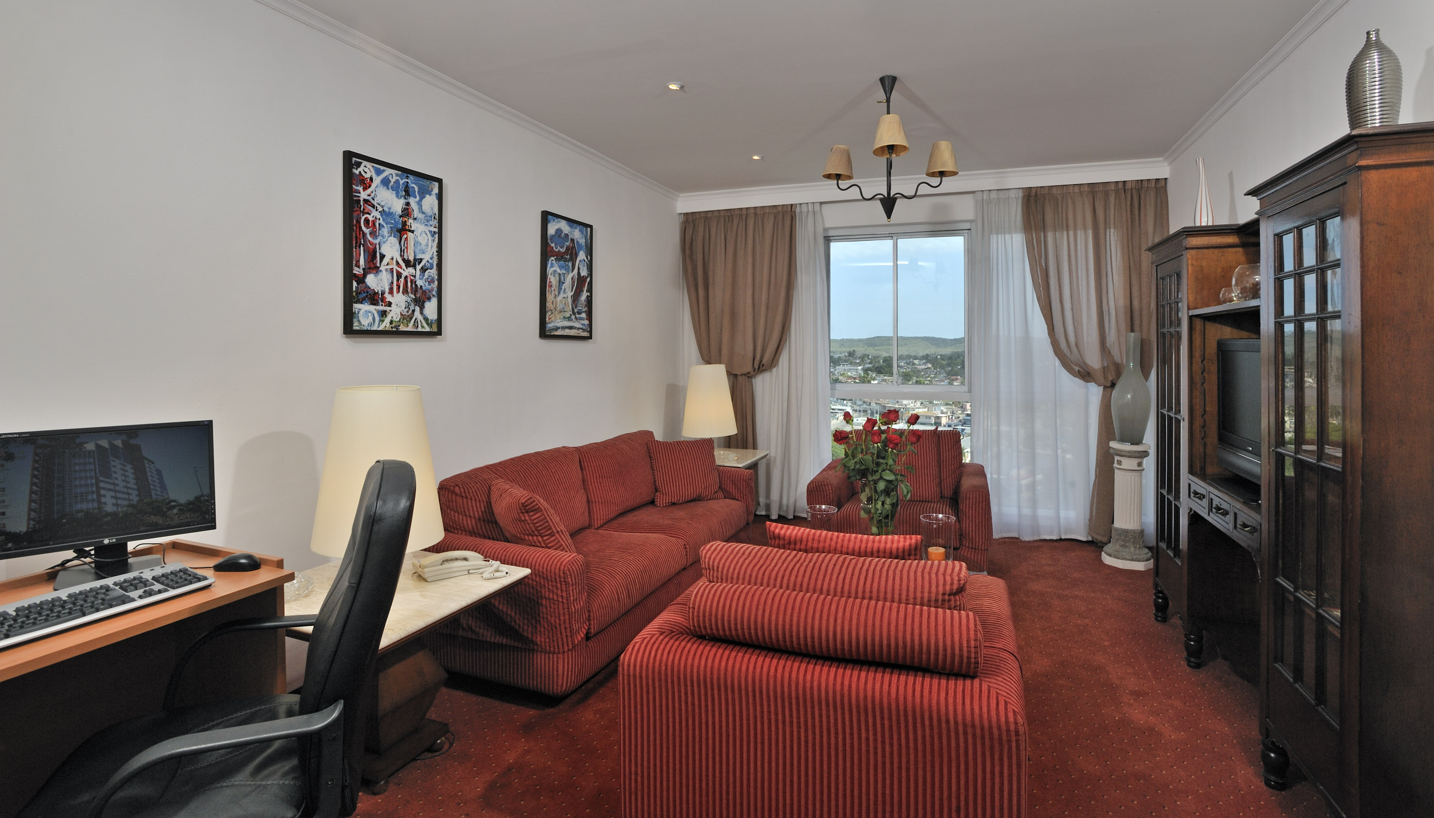 a living room with red couches and a desk