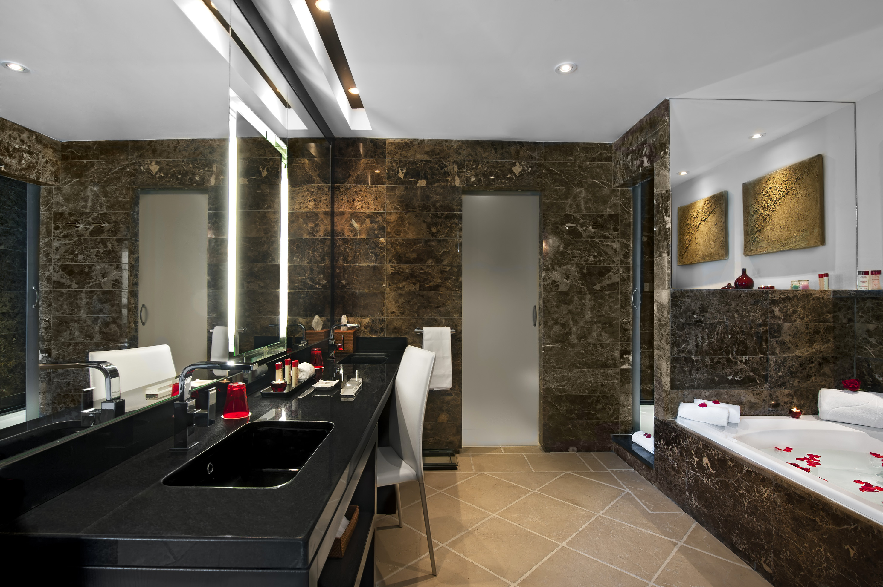 Modern luxury bathroom with dark marble, double vanity, black sinks, bathtub.