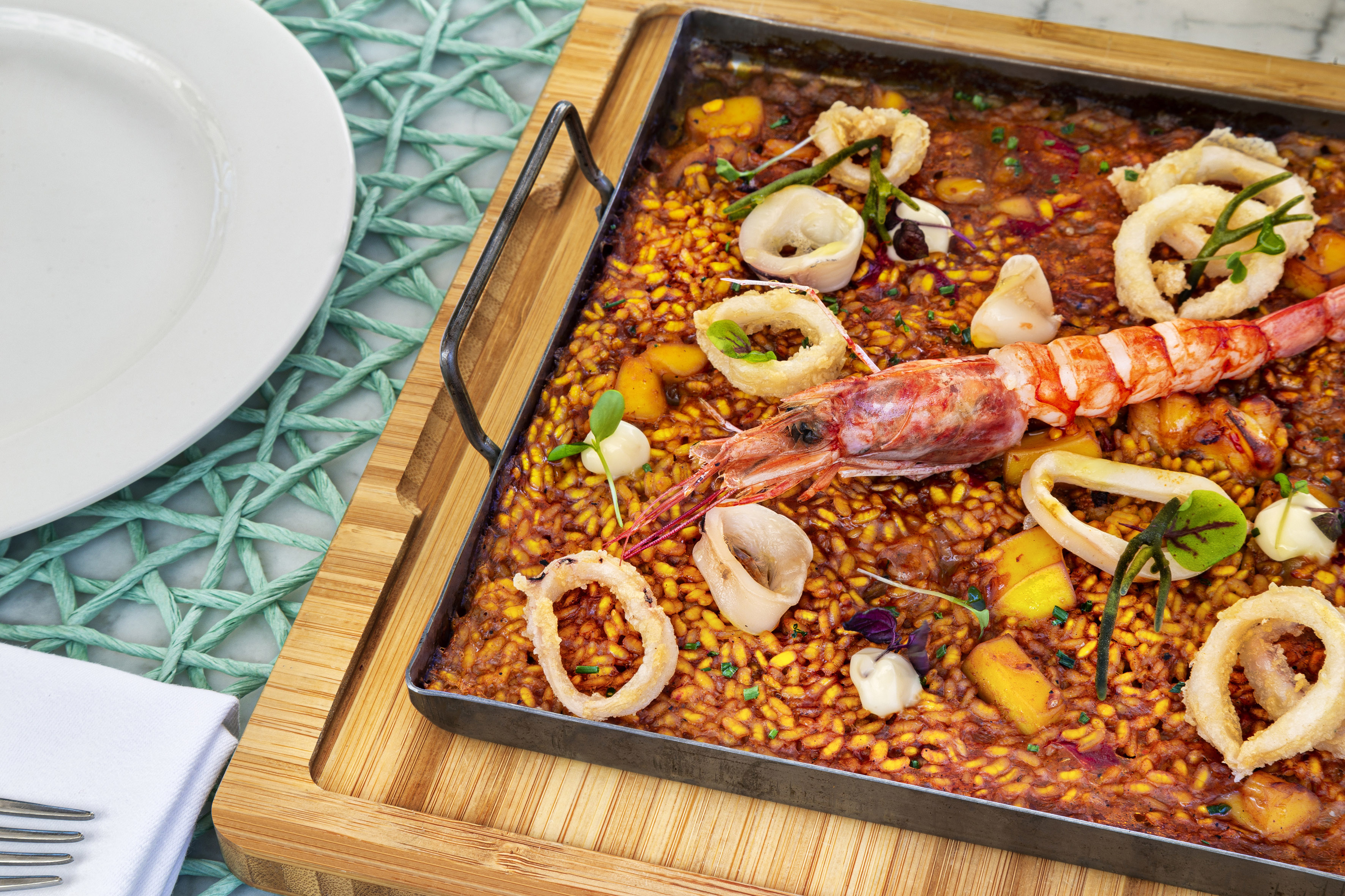 Seafood paella pan with large prawn and fried calamari rings.