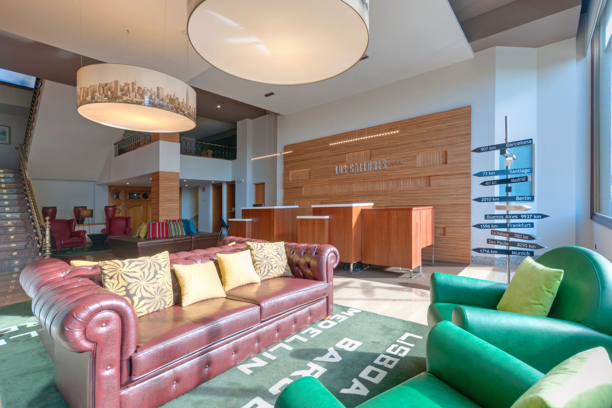 Hotel lobby with sofas, reception, city rug, and global destinations sign.