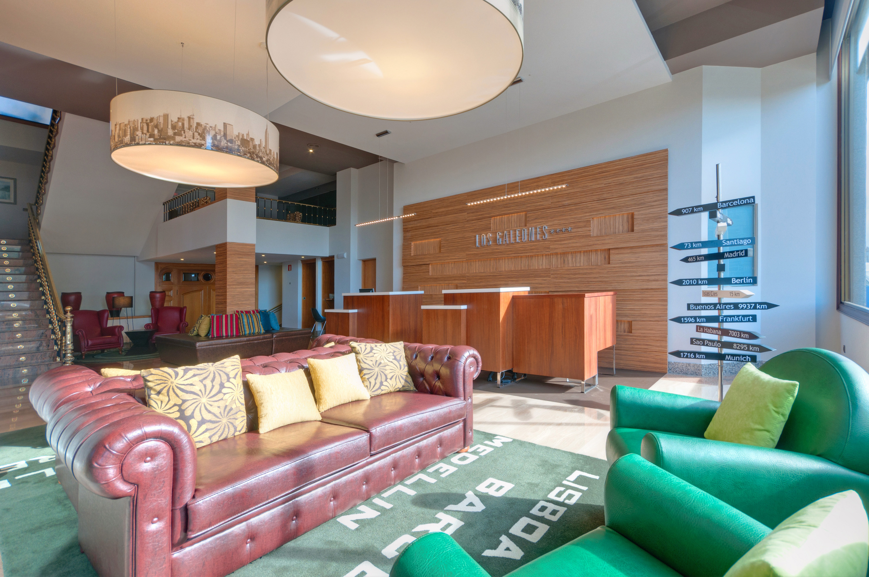 Hotel lobby with sofas, reception, city rug, and global destinations sign.