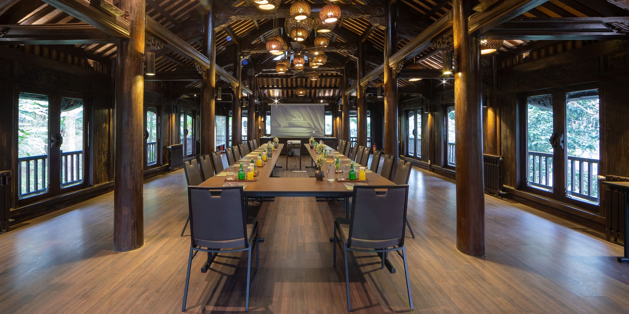 a long table with chairs and a projector from the ceiling