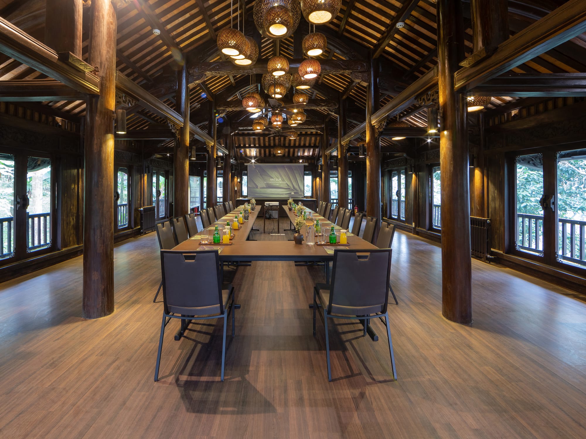 a long table with chairs and a projector from the ceiling