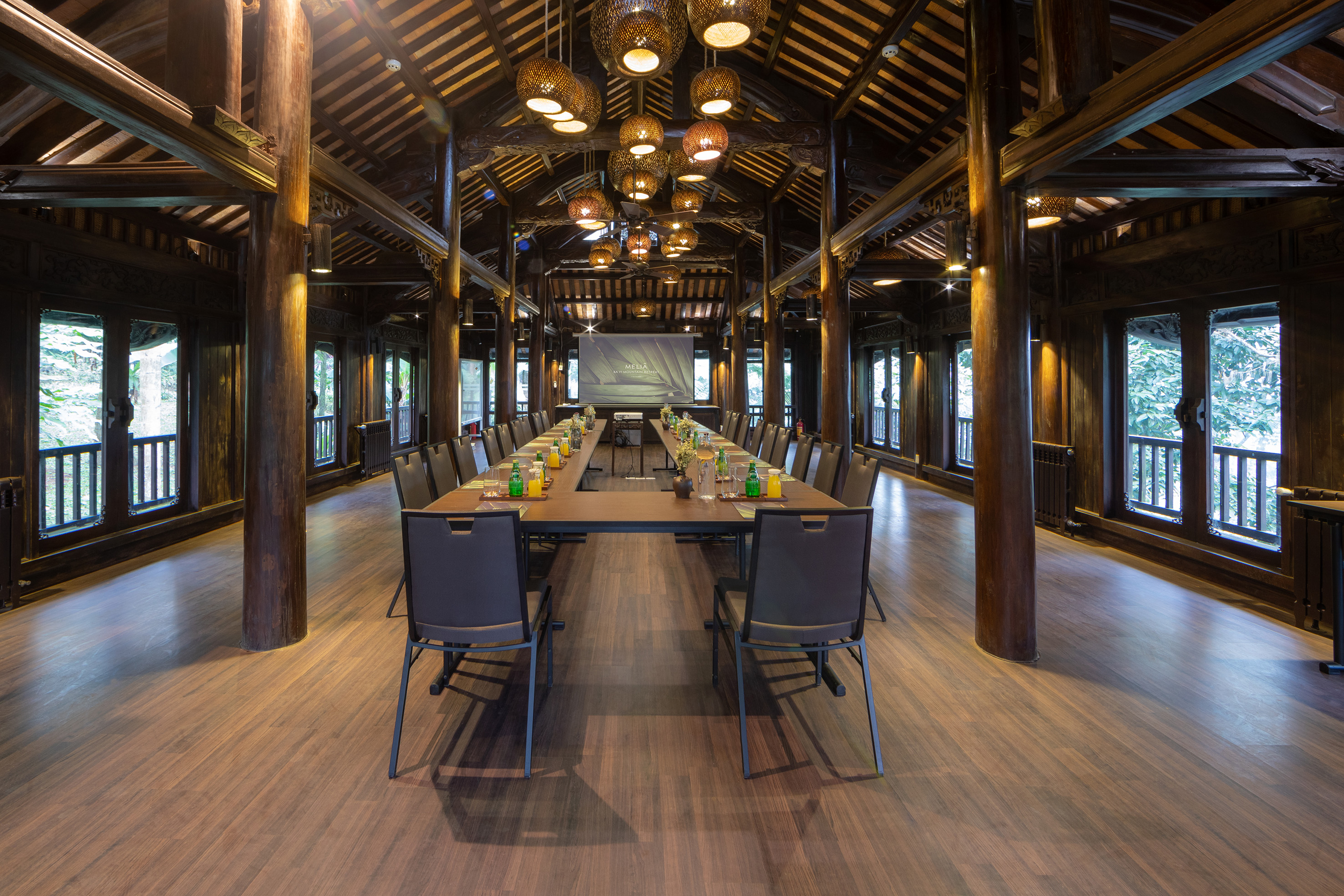 a long table with chairs and a projector from the ceiling