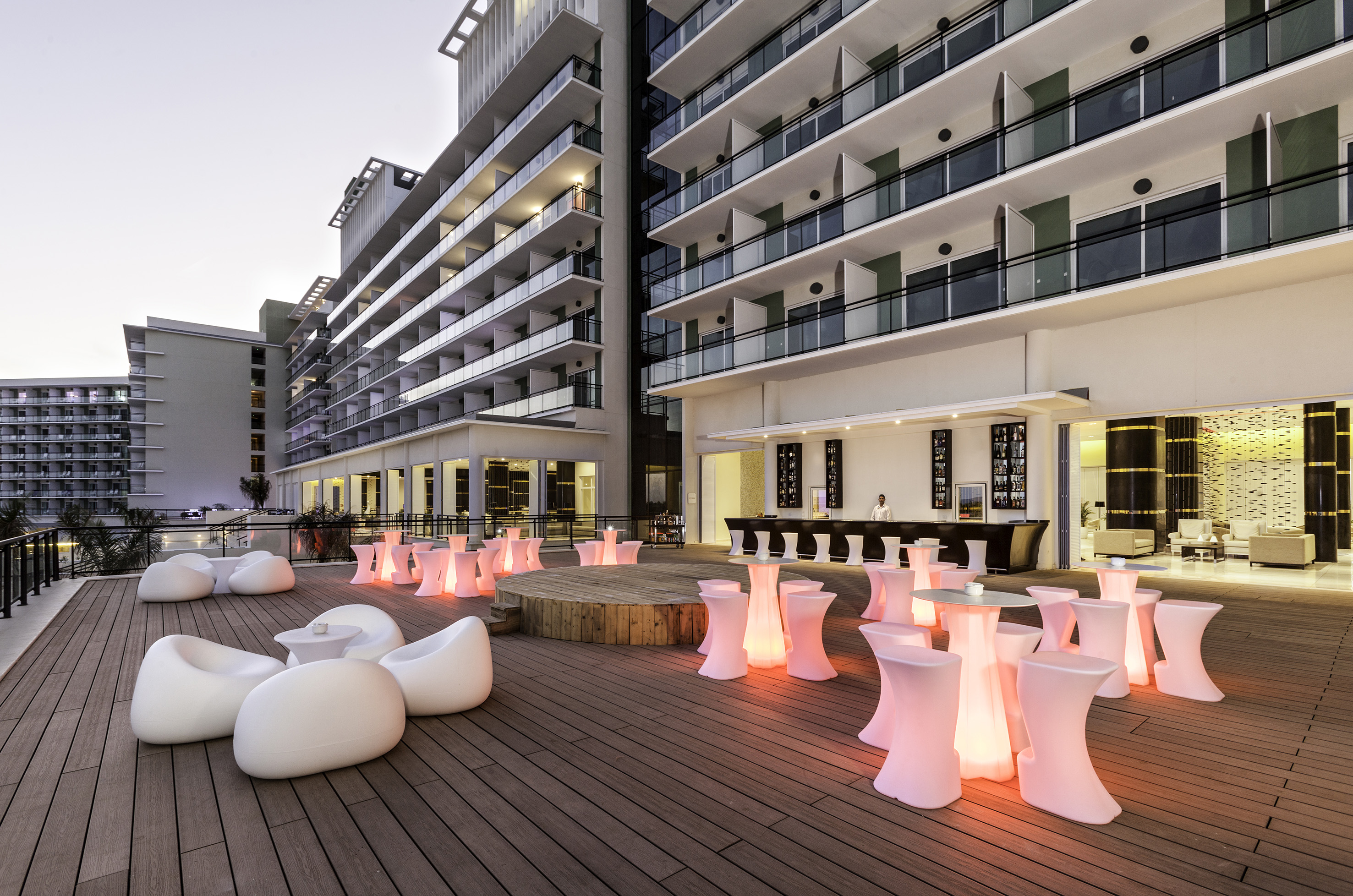 a patio with white chairs and tables with pink lights