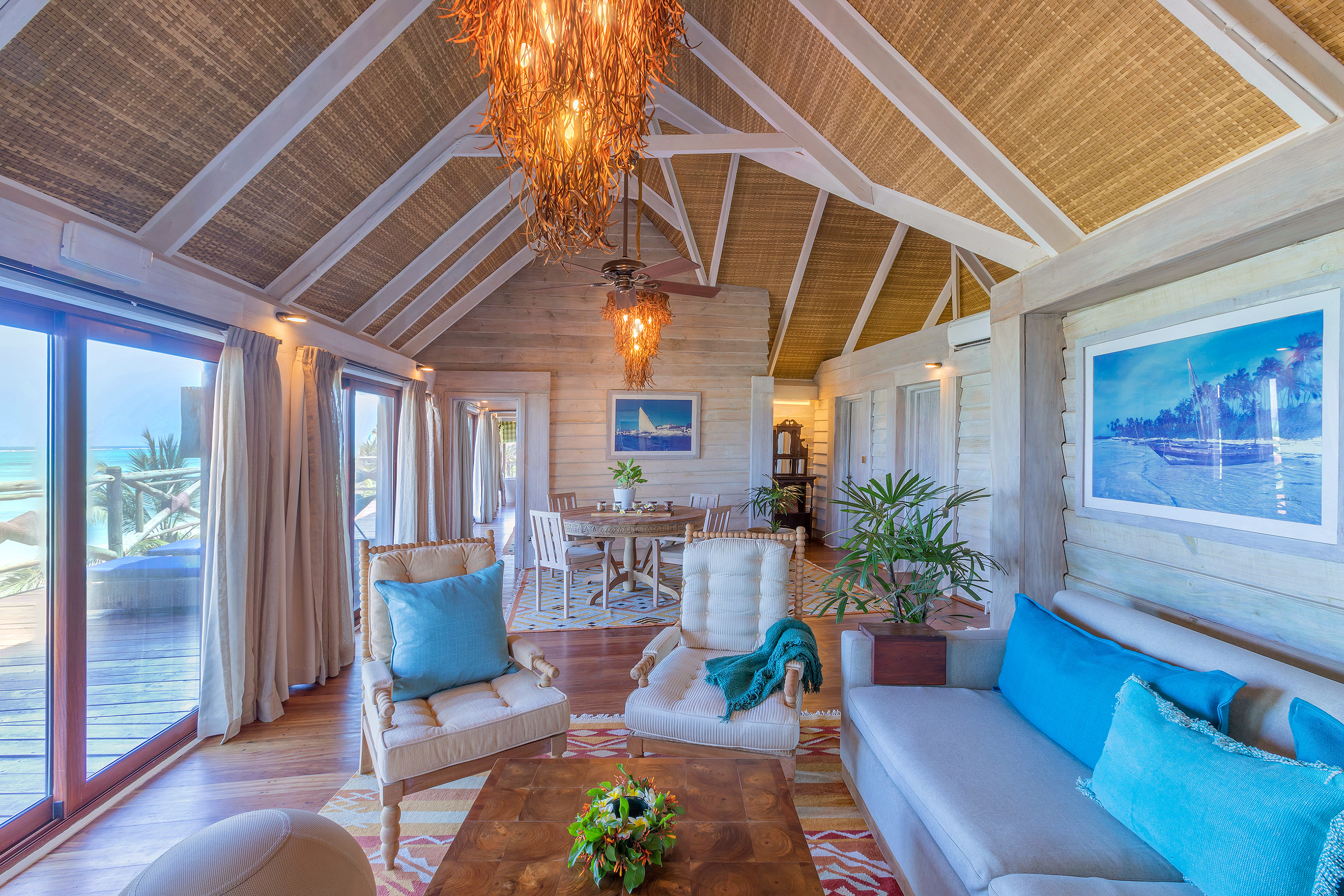Tropical villa living room with ocean view, woven ceiling, and coastal decor.