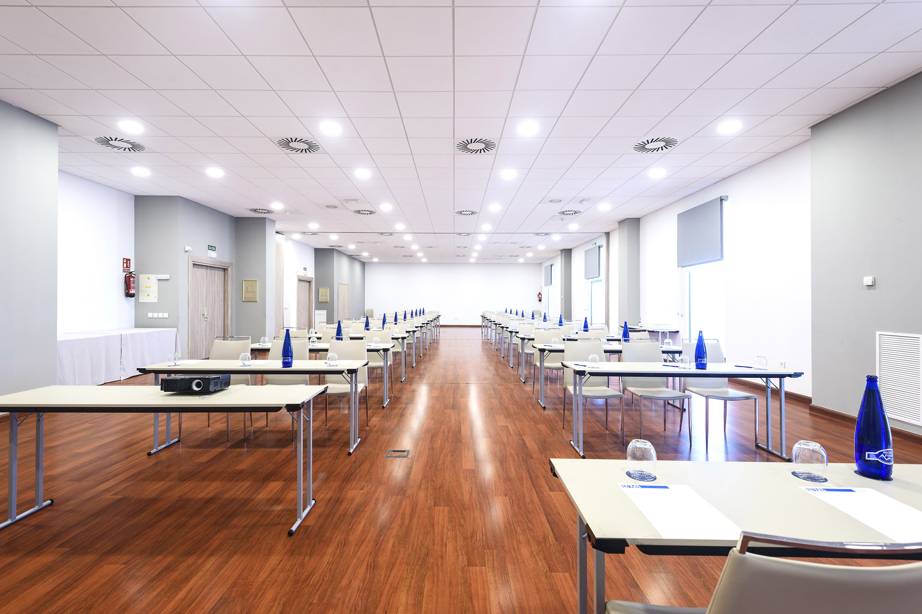 Empty modern conference room with tables, chairs, and projector.