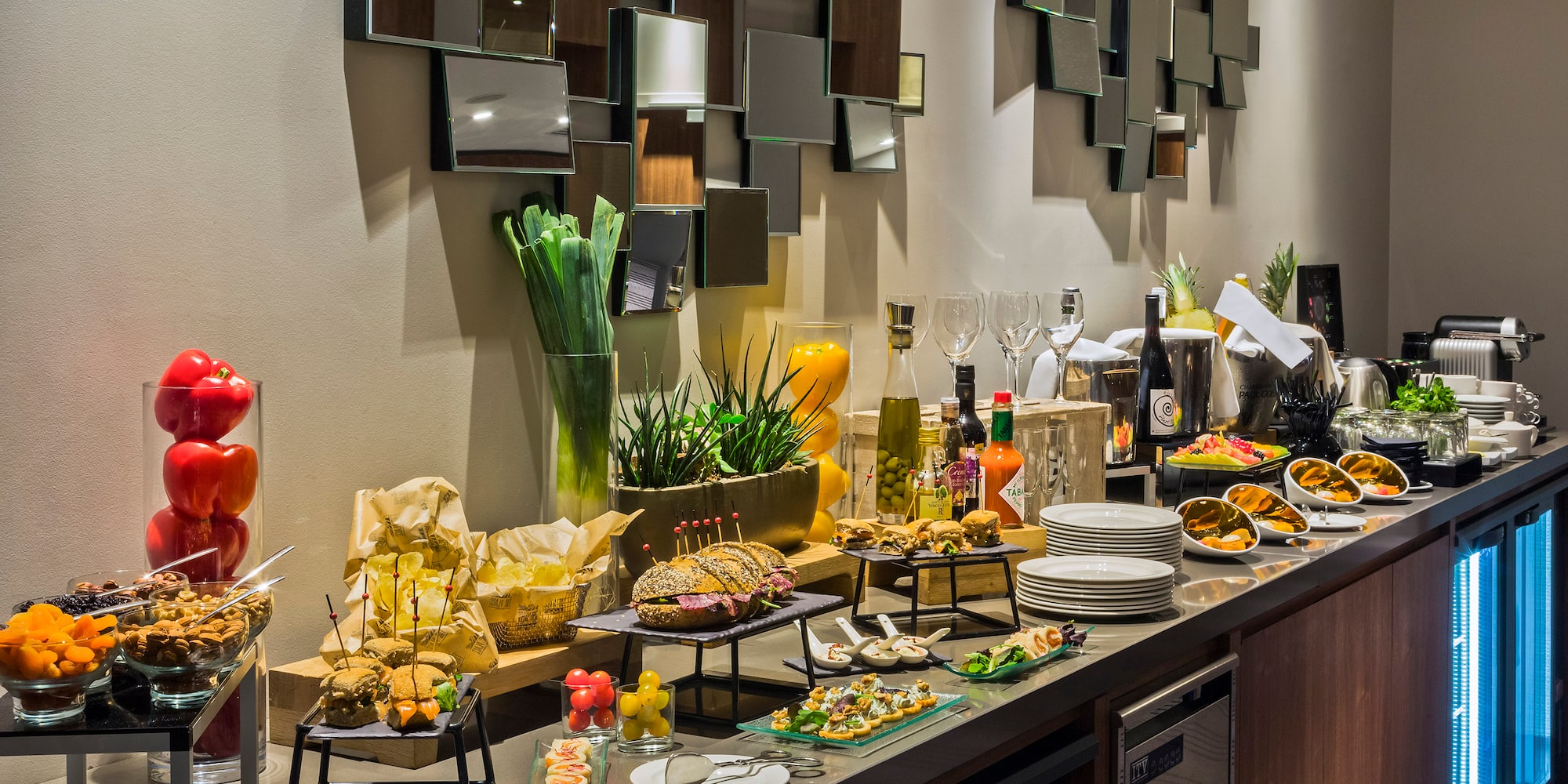 Hotel buffet spread with sandwiches, appetizers, fresh fruit, and drinks.
