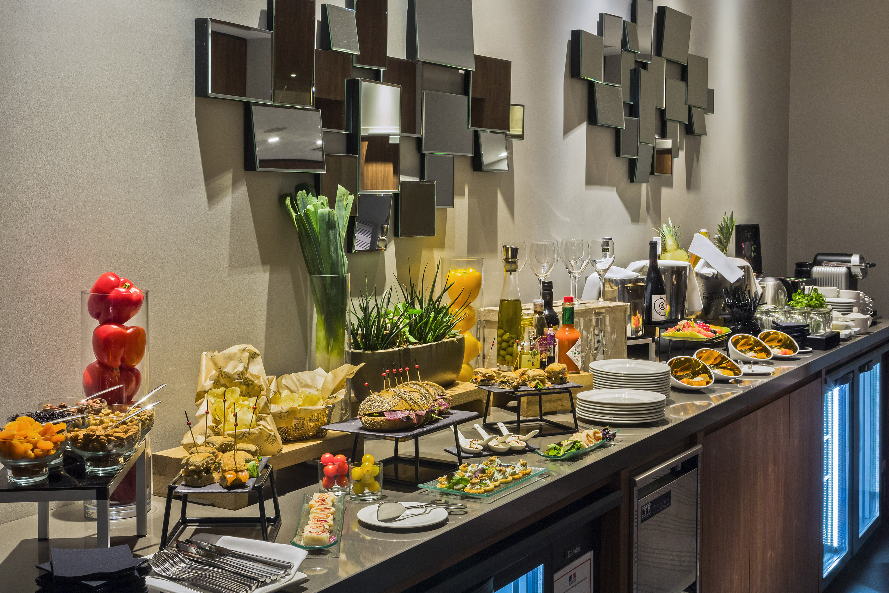 Hotel buffet spread with sandwiches, appetizers, fresh fruit, and drinks.