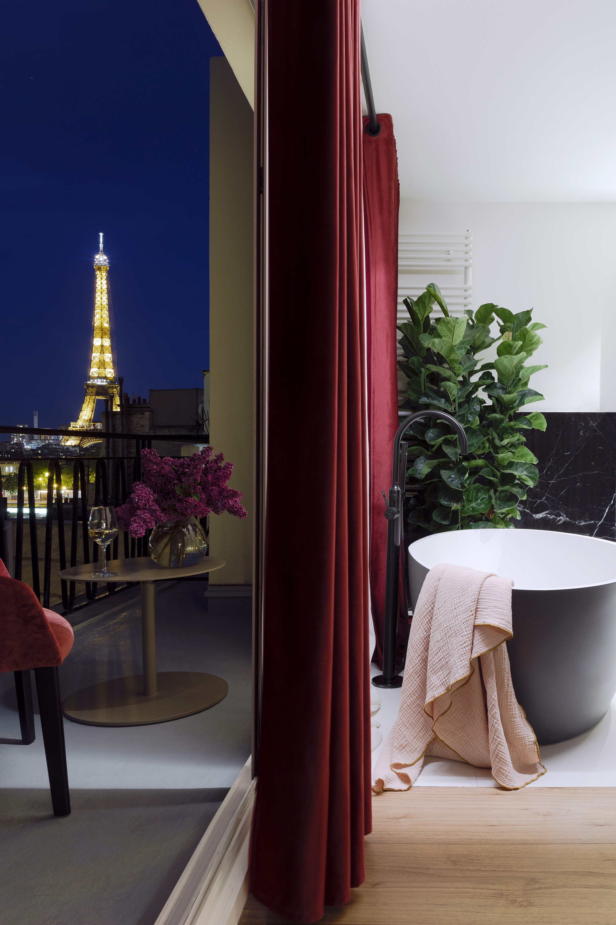 Paris balcony with Eiffel Tower night view, next to a modern bathroom.
