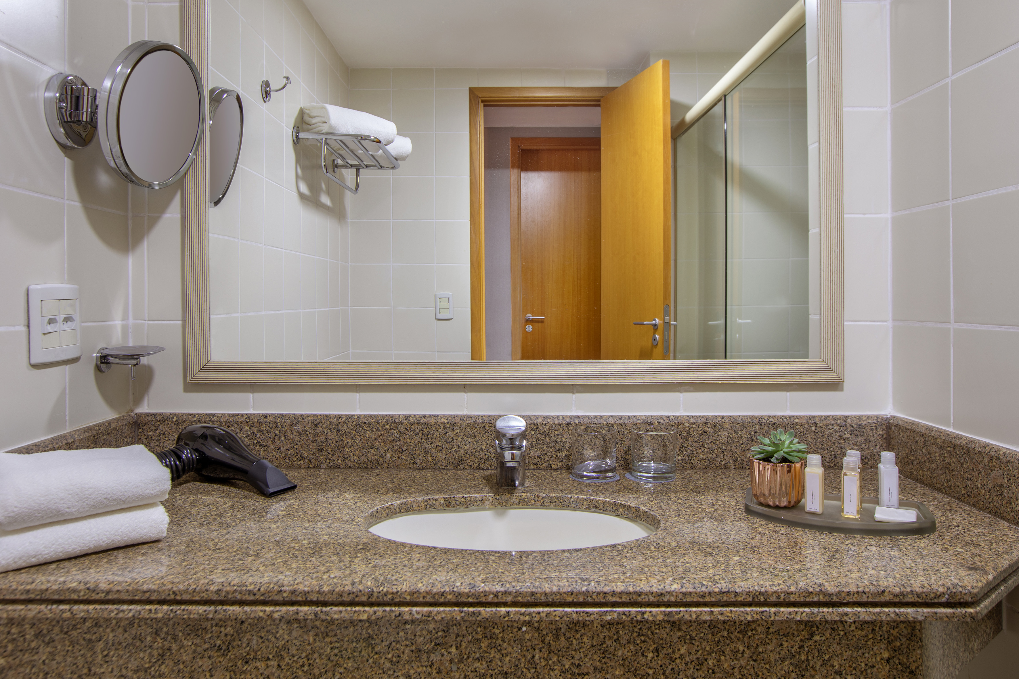 Hotel bathroom with granite vanity, sink, mirror, towels, and toiletries.
