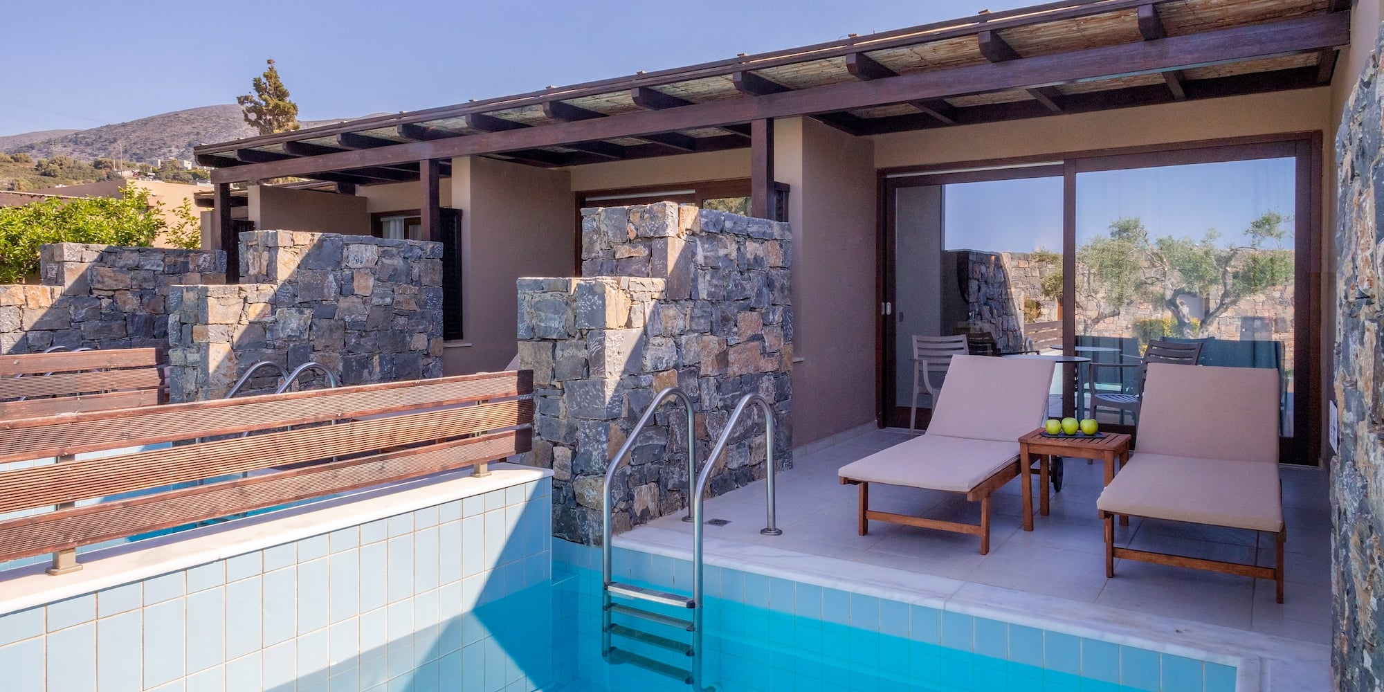 a pool with chairs and a deck chair in front of a house