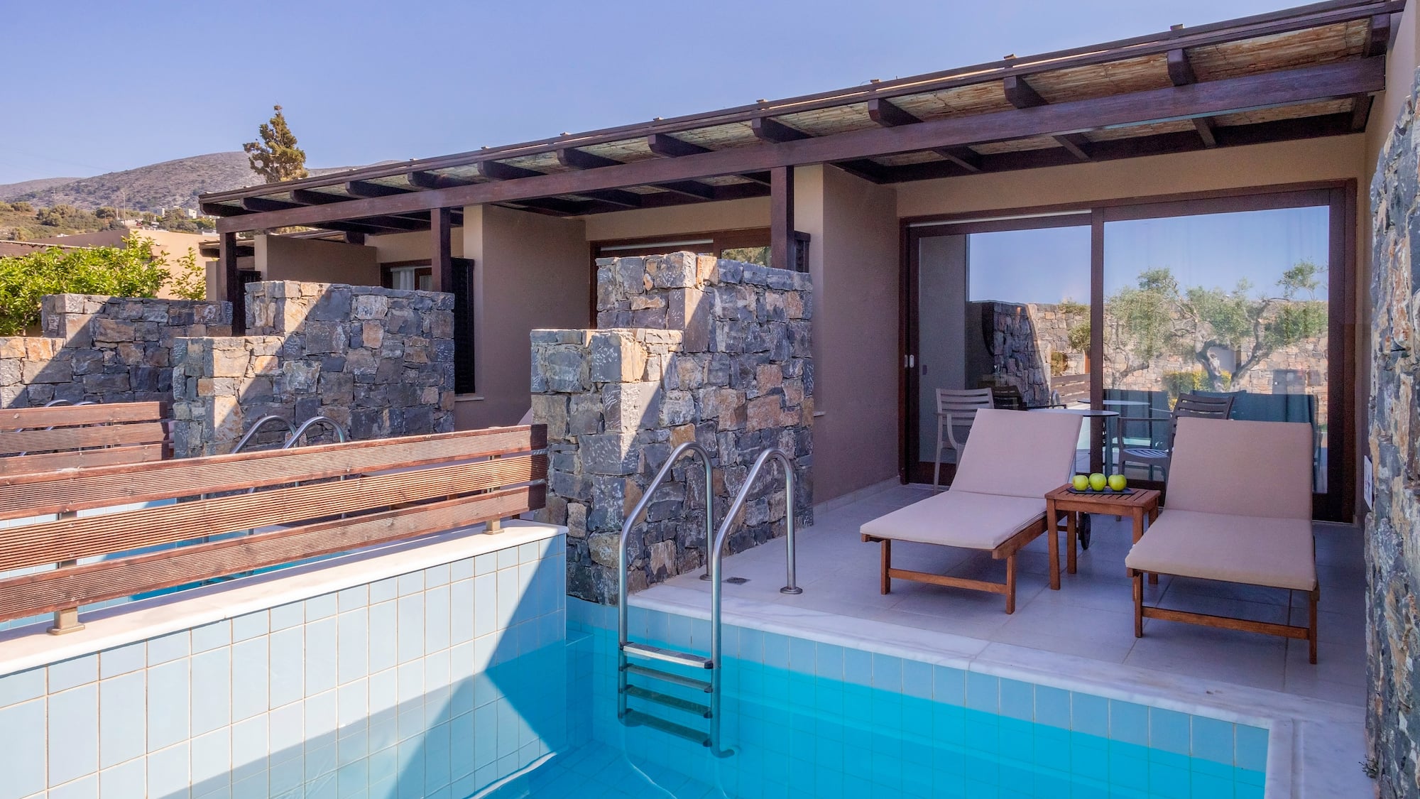 a pool with chairs and a deck chair in front of a house