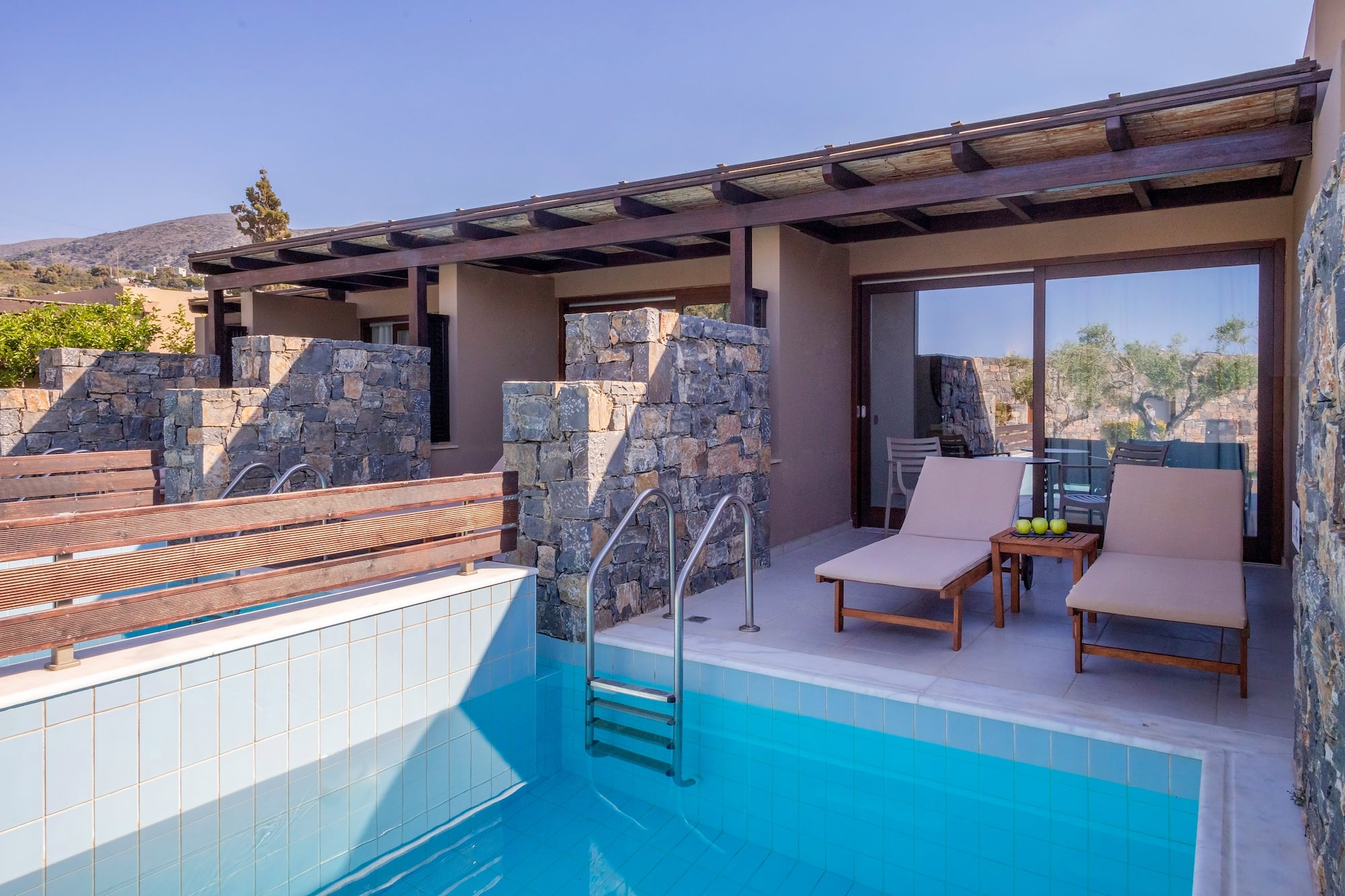 a pool with chairs and a deck chair in front of a house
