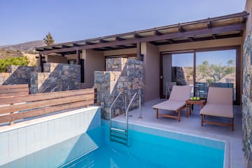 a pool with chairs and a deck chair in front of a house
