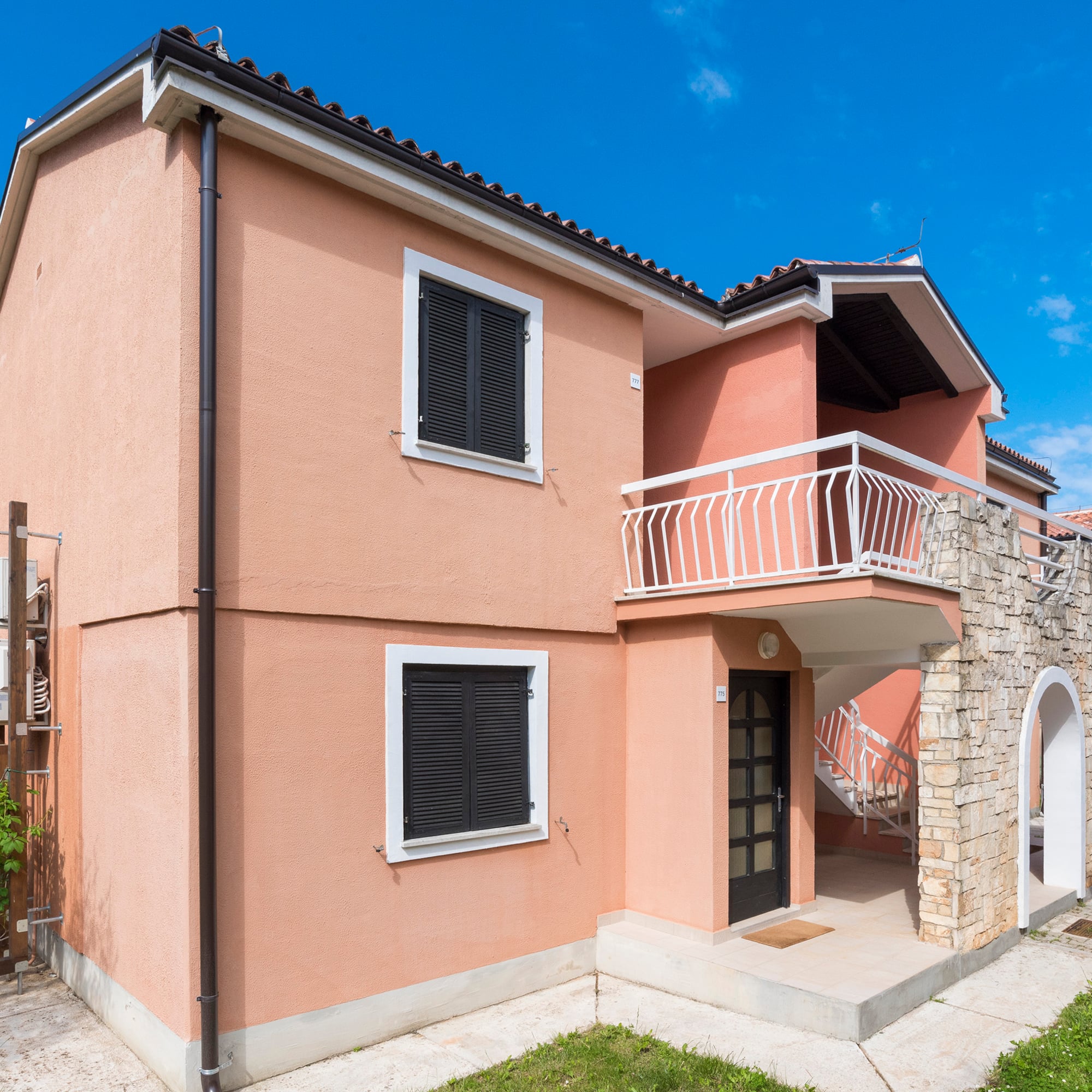 a house with a stone wall and a balcony