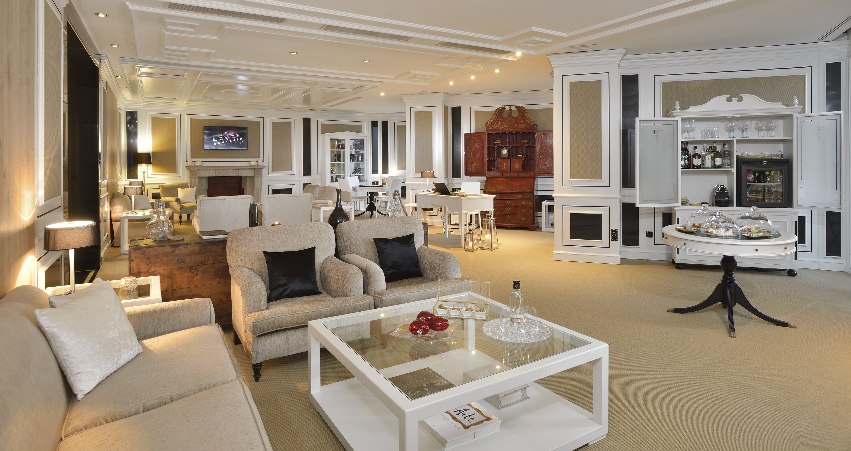 Elegant luxury lounge with sofas, working desk, and integrated refreshments bar.