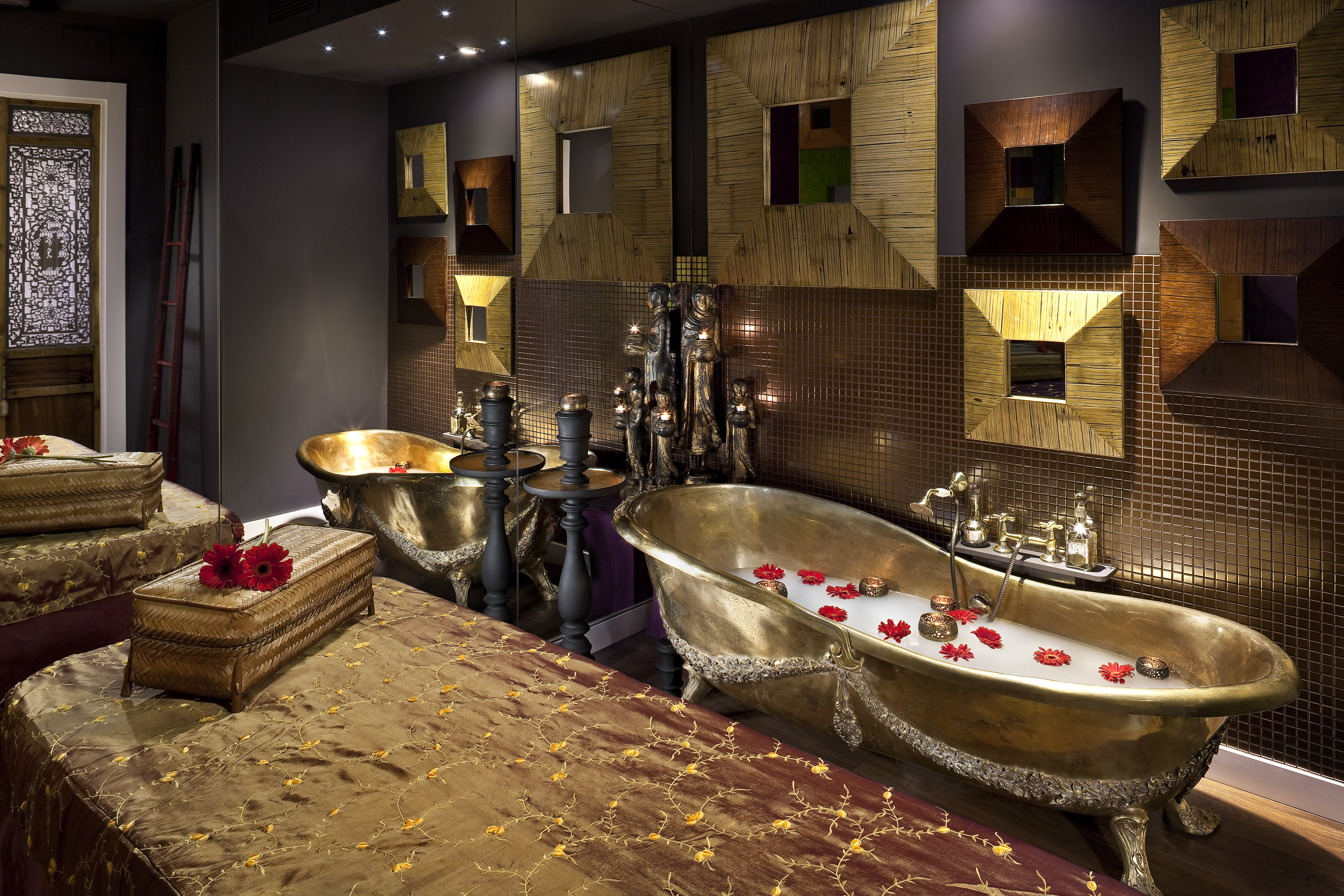 Luxurious spa: two golden ornate bathtubs with milk and red flowers, elegant decor.