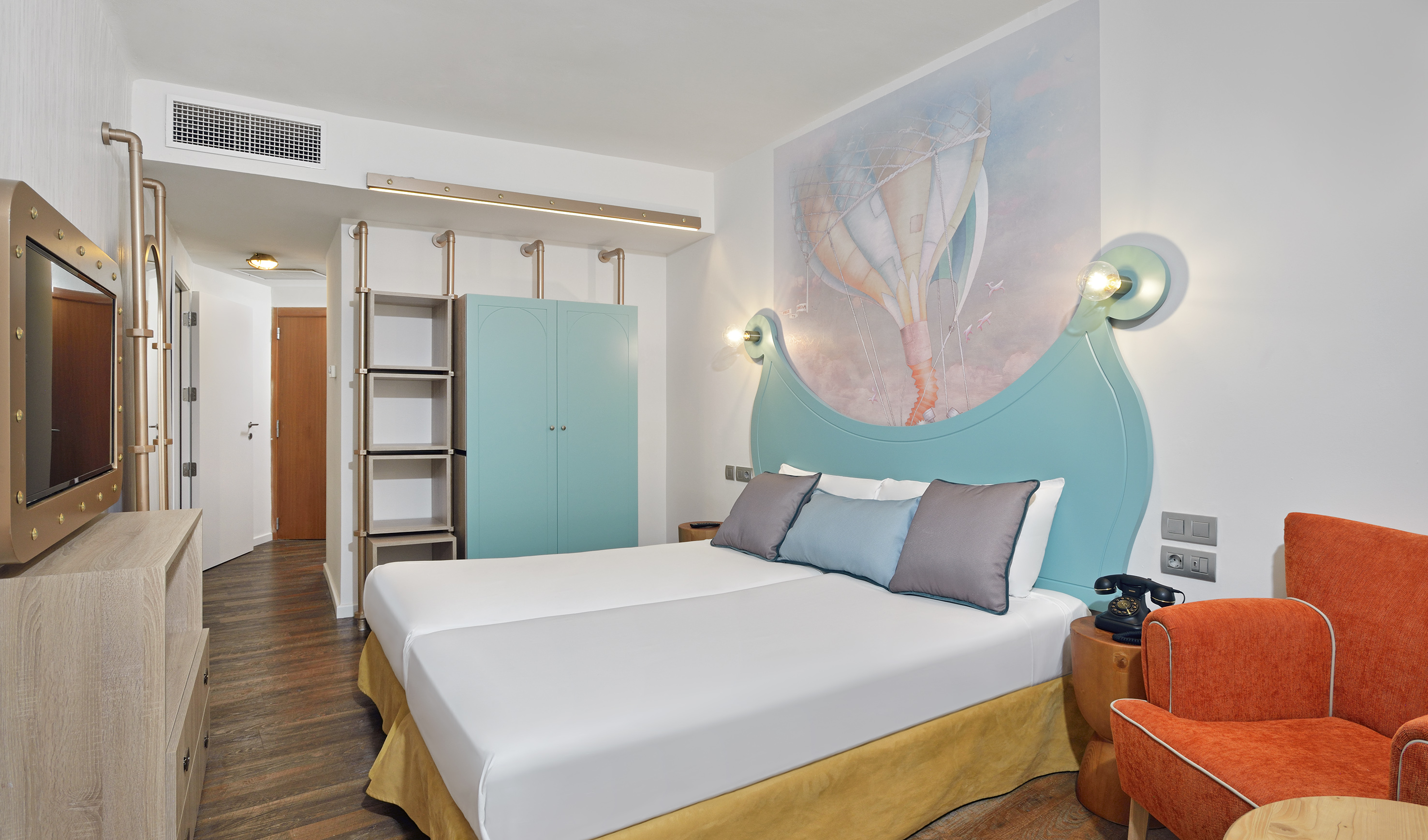 Vibrant hotel room with hot air balloon mural, twin beds, and unique industrial decor.
