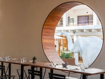 a table with chairs and a large elephant statue in the window