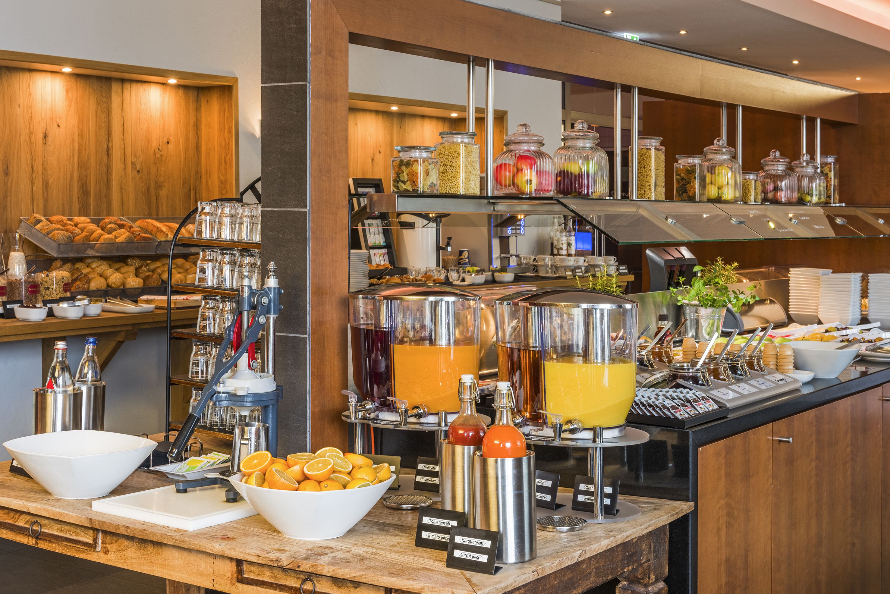 Hotel breakfast buffet with fresh orange juice, baked goods, and cereal jars.
