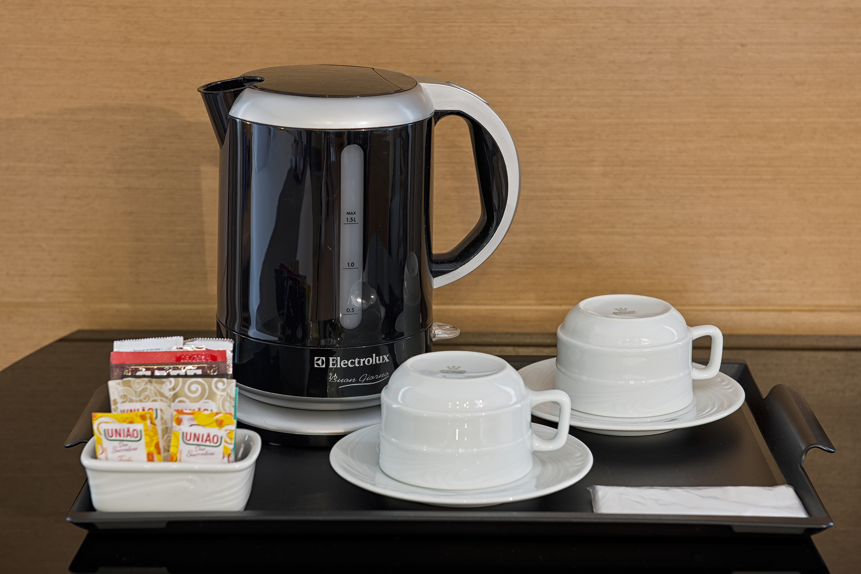 Hotel coffee tea station: Electrolux electric kettle, white cups, sugar on tray.
