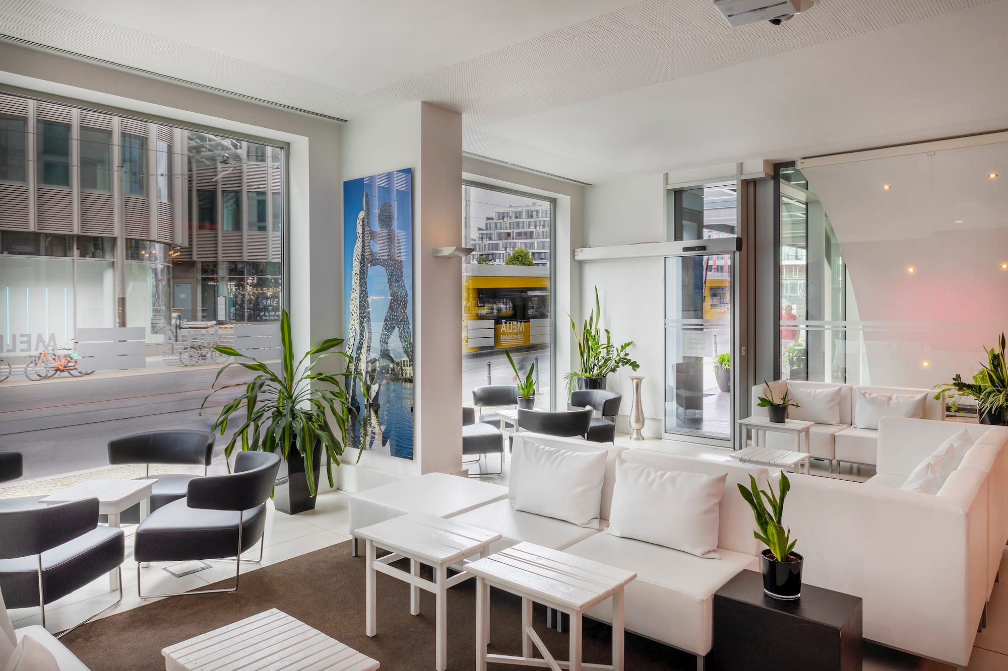 Modern hotel lounge with white modular sofas, black chairs, and city view.