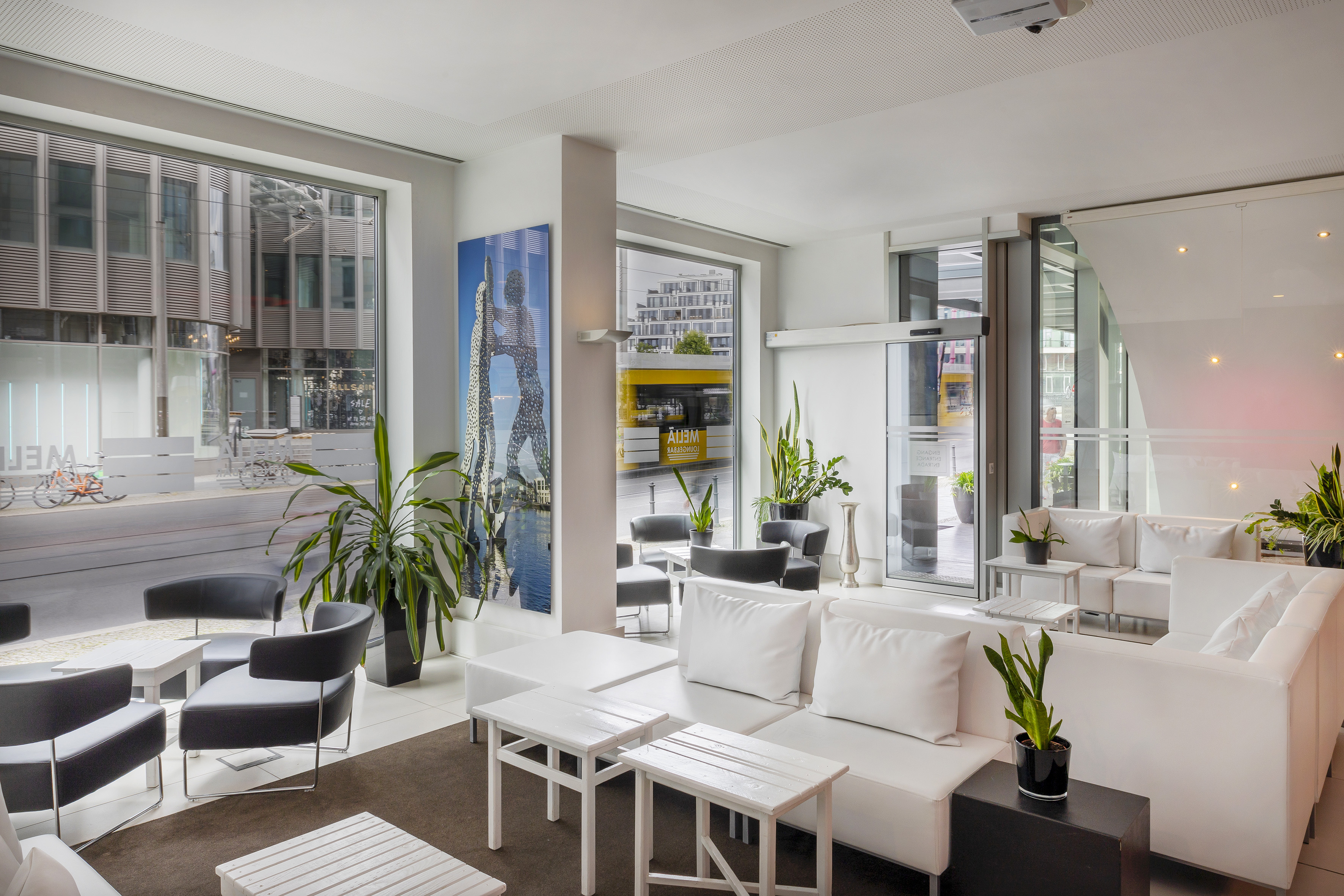 Modern hotel lounge with white modular sofas, black chairs, and city view.