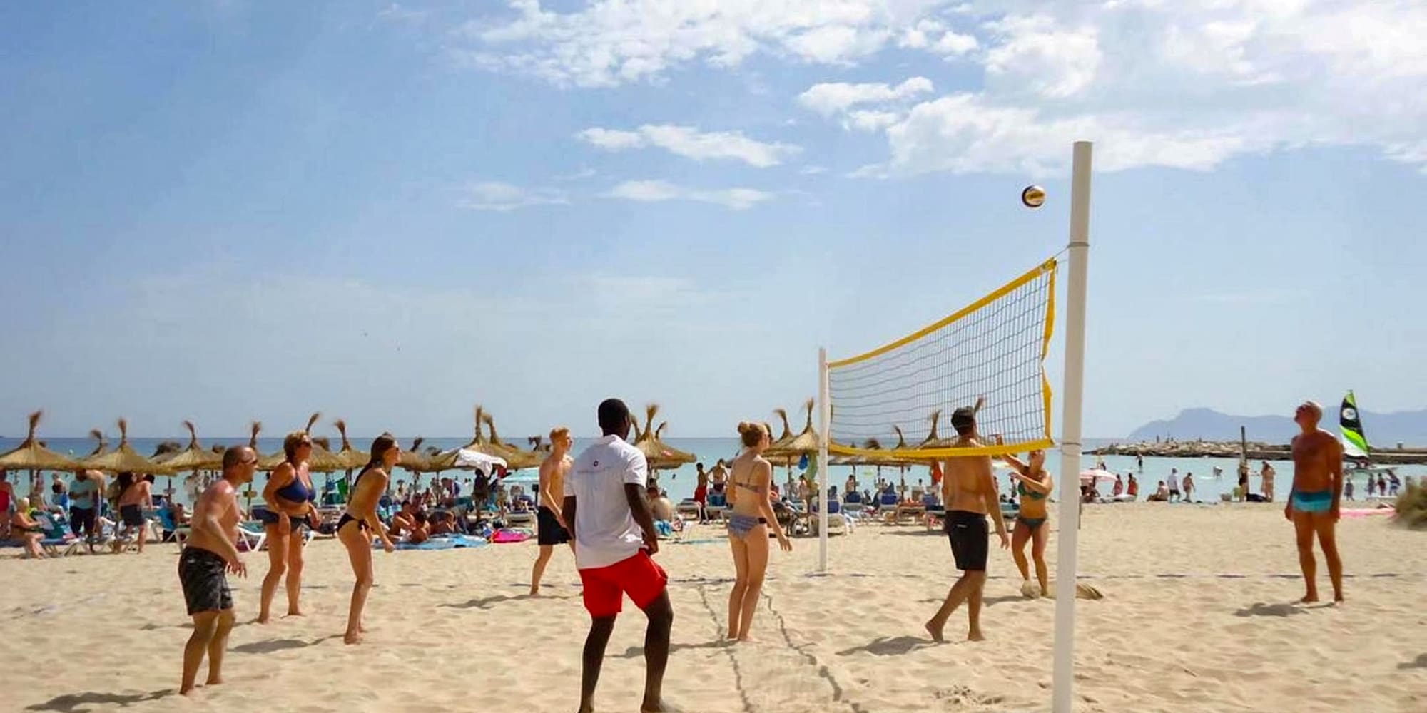 a group of people playing volleyball on a beach