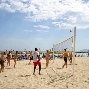 a group of people playing volleyball on a beach