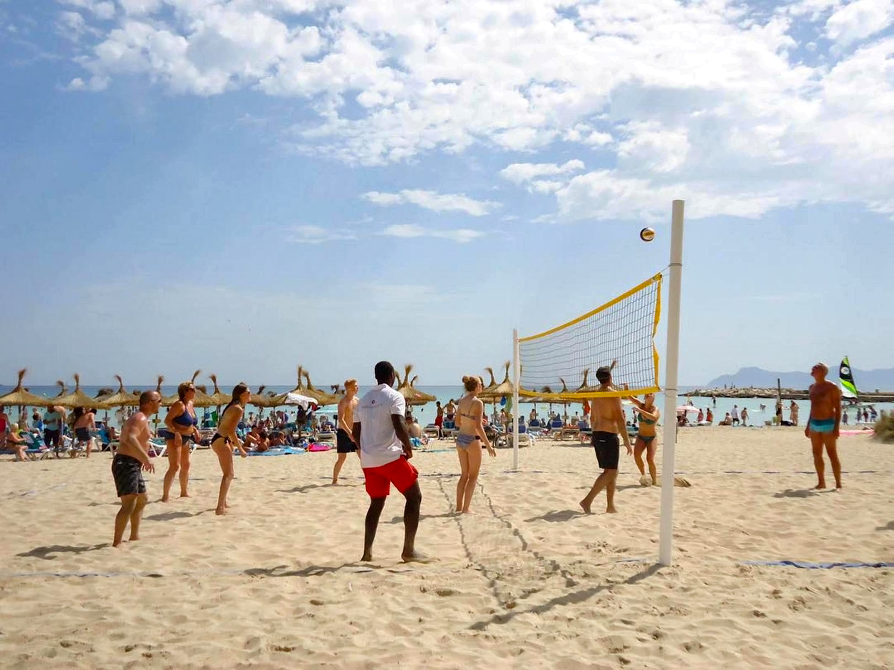 a group of people playing volleyball on a beach