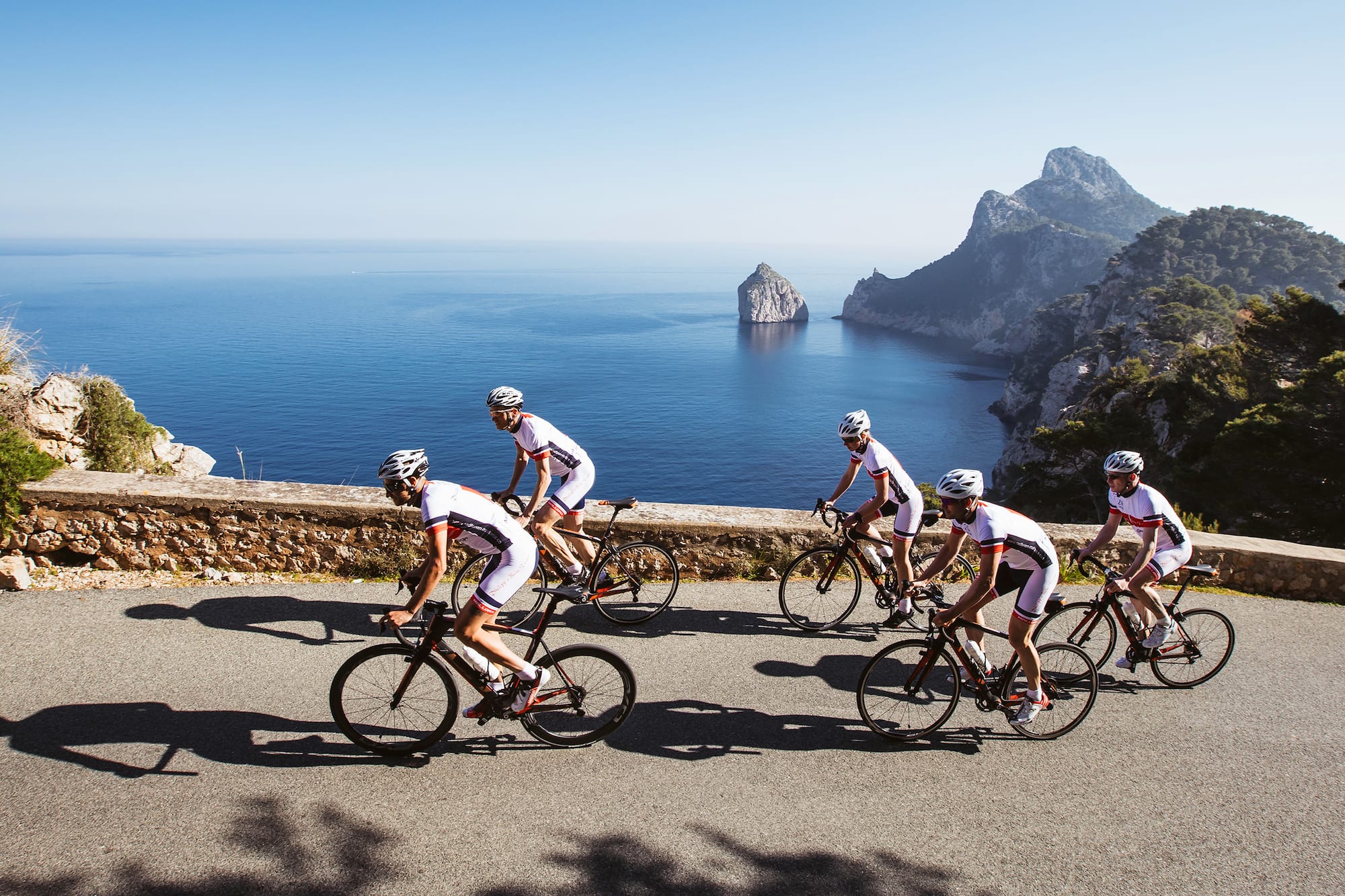 a group of people riding bicycles on a road near water
