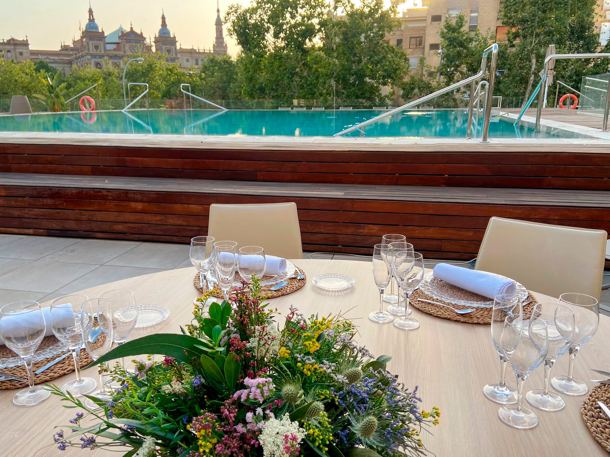a table set for a dinner with a pool in the background