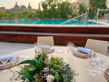 a table set for a dinner with a pool in the background
