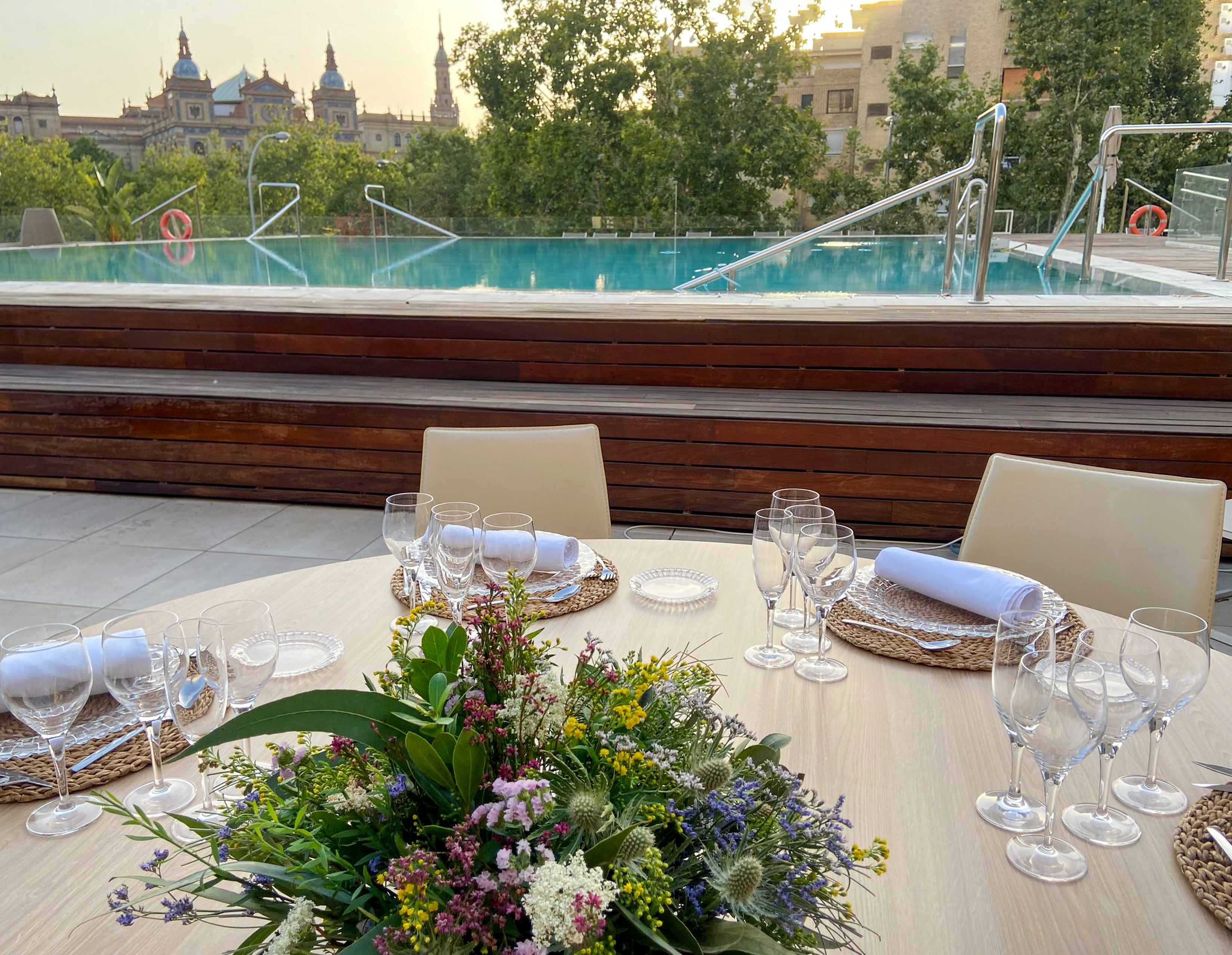 Rooftop dining, floral table setting, infinity pool, historic Seville views.