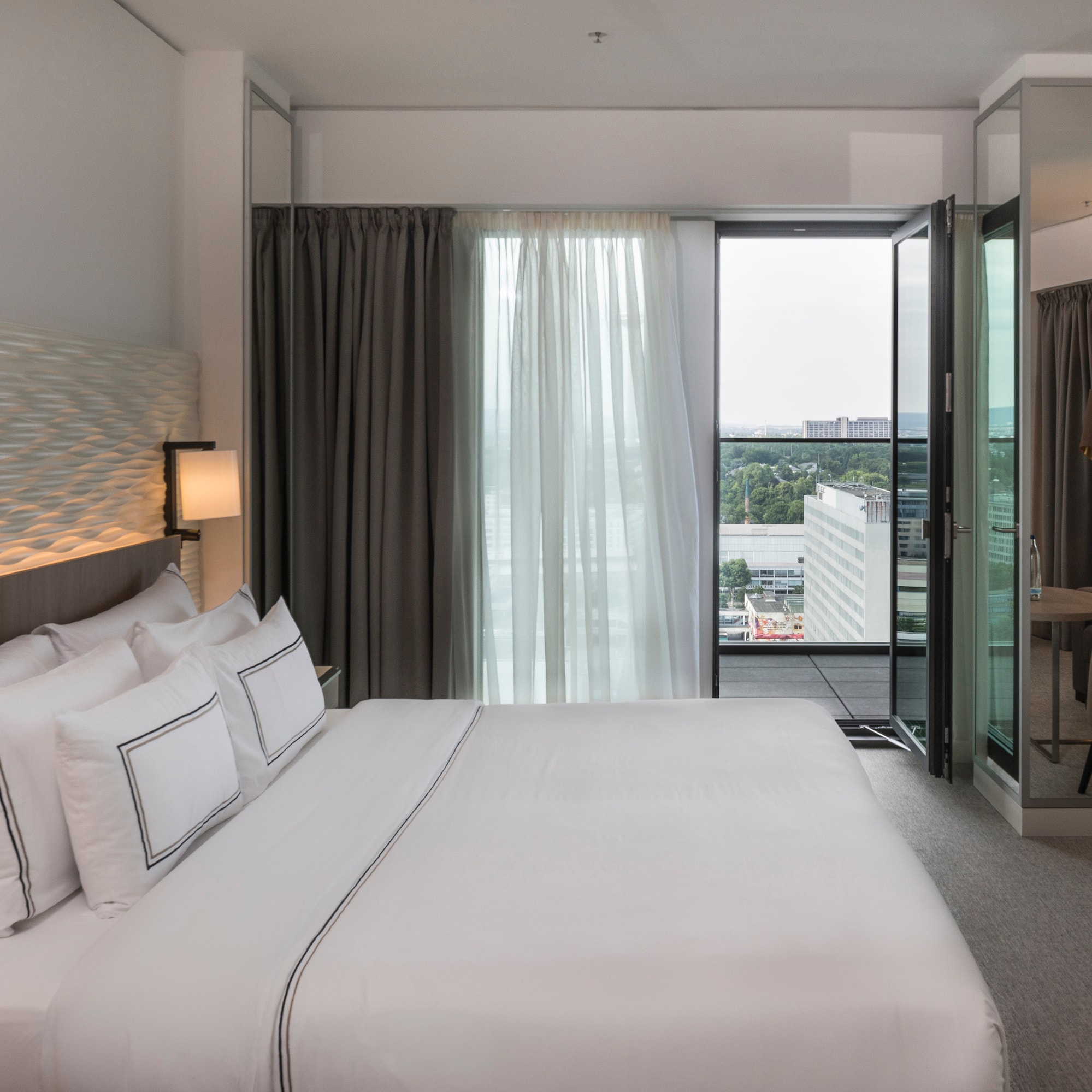 a bed with white sheets and a lamp in a hotel room