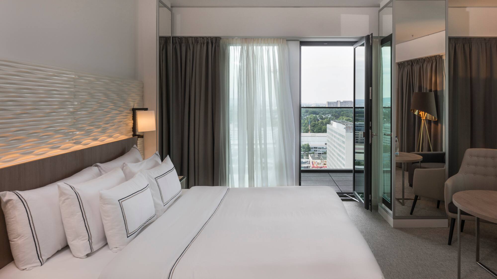 a bed with white sheets and a lamp in a hotel room