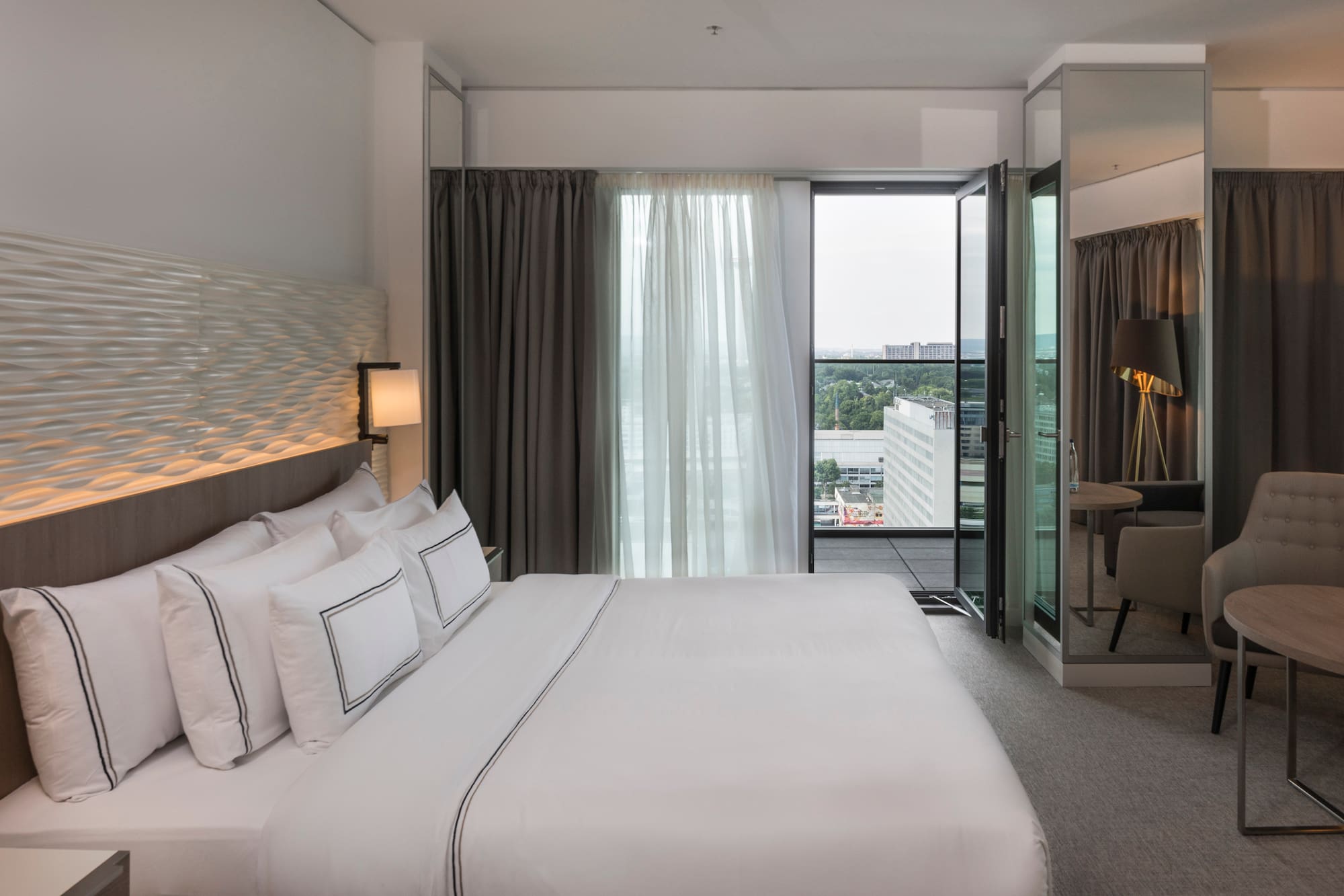 a bed with white sheets and a lamp in a hotel room