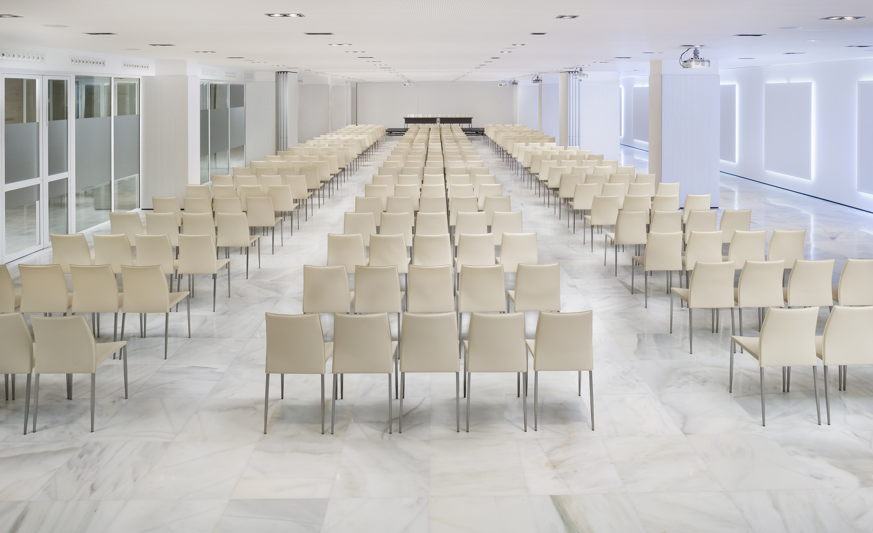 Empty modern conference room with rows of cream chairs and a presentation stage.