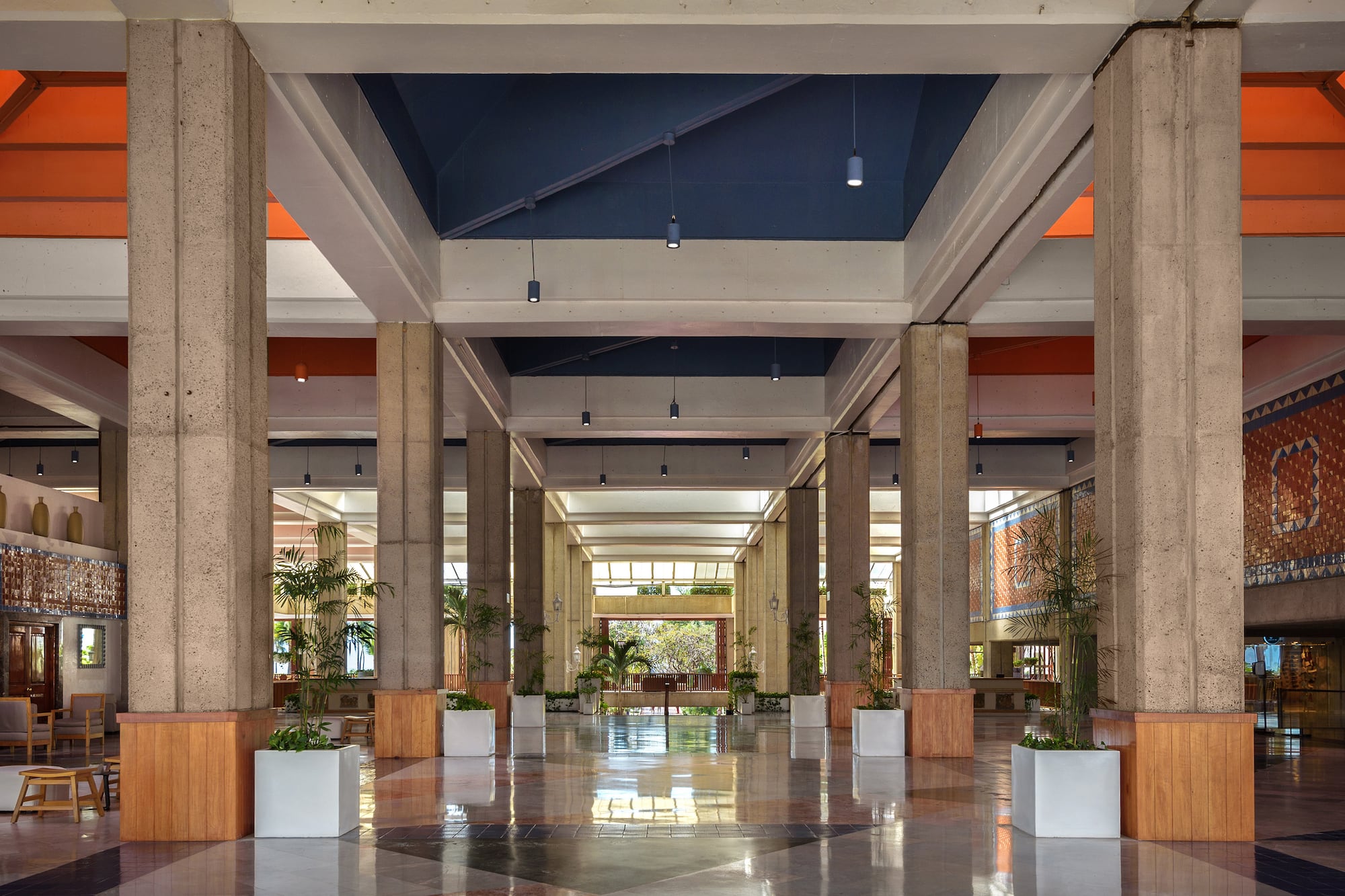 a large hall with columns and plants