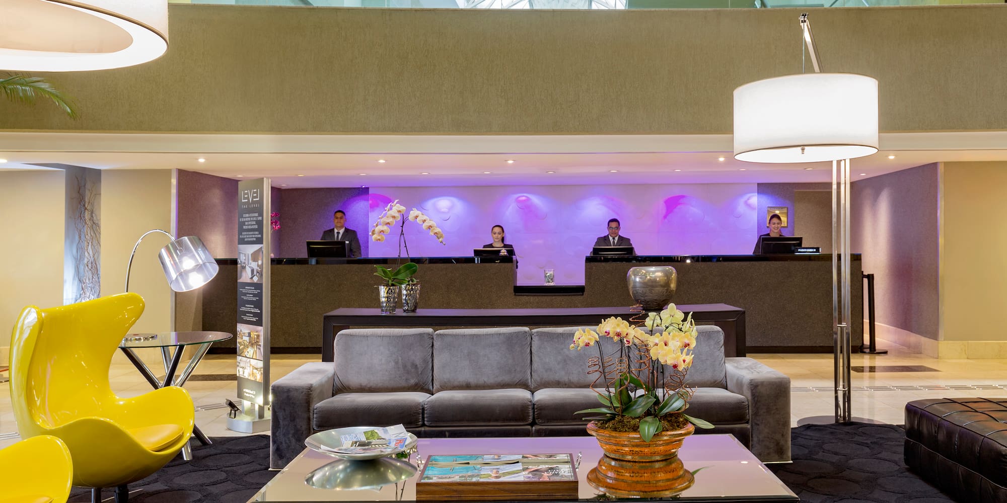 a lobby with a couch and a table with a lamp and people behind it