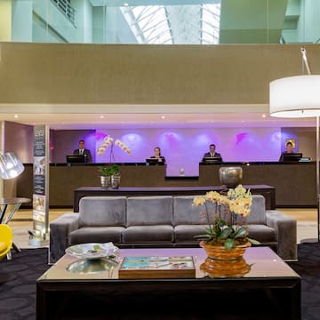 a lobby with a couch and a table with a lamp and people behind it