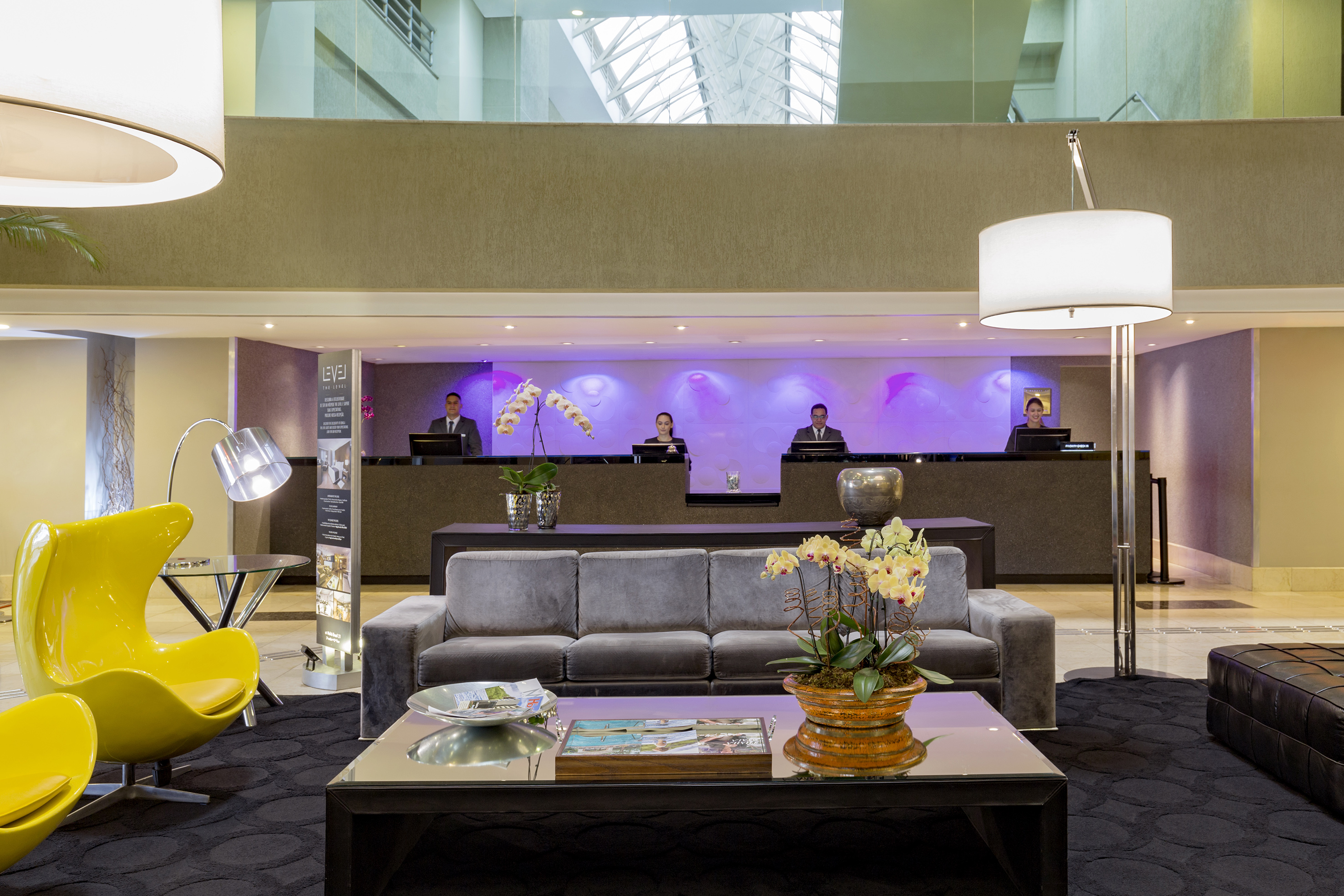 a lobby with a couch and a table with a lamp and people behind it