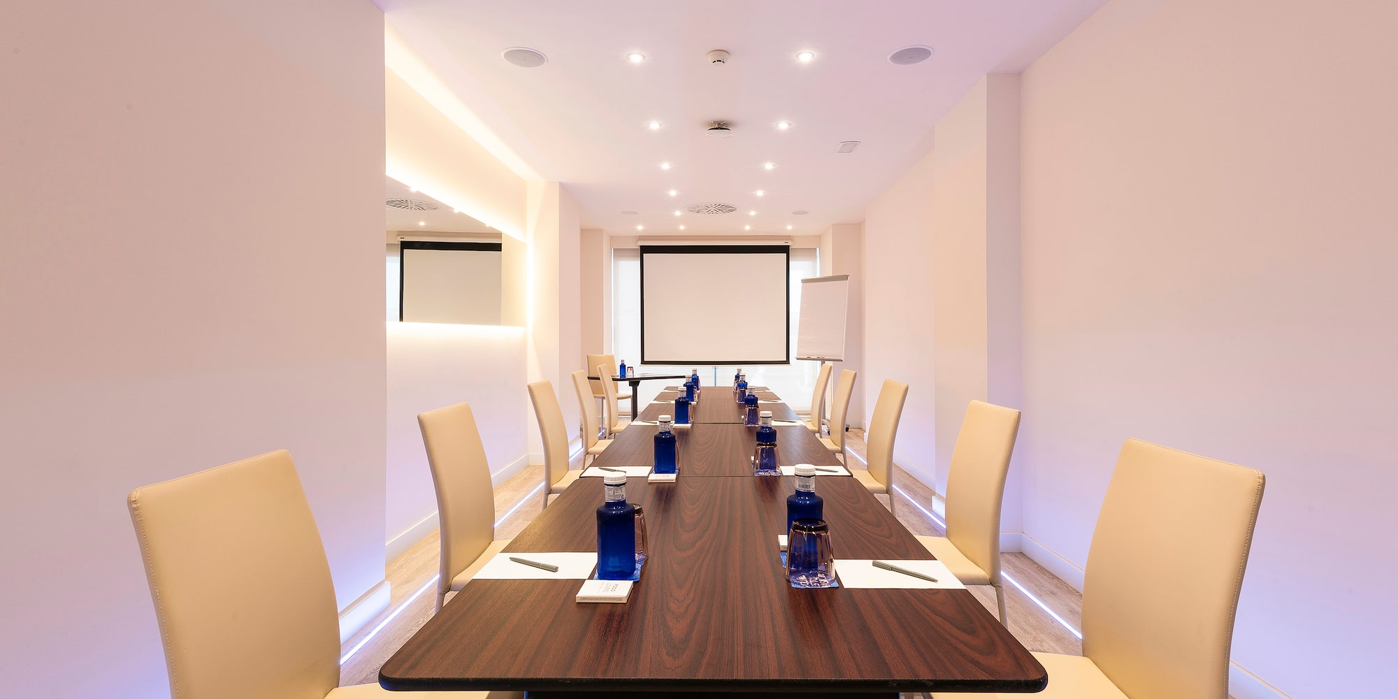 a long conference table with chairs and a projector screen